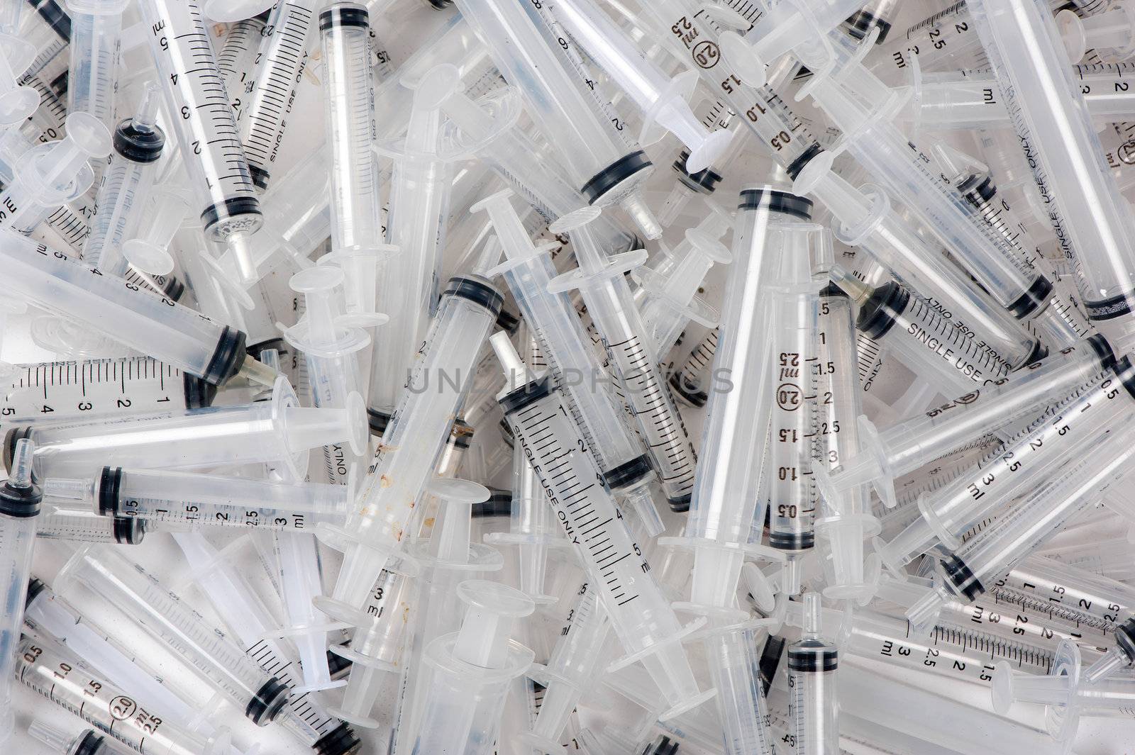 Many used syringes lie strewn on a flat surface.