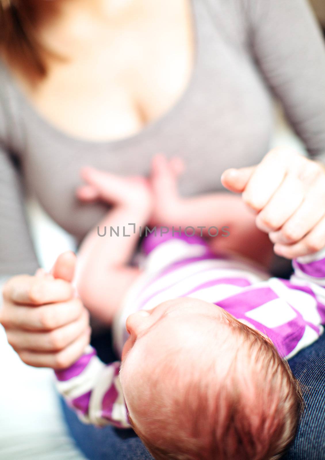 View from the top of the head of a tiny baby lying on its back on the lap of its loving mother with shallow dof