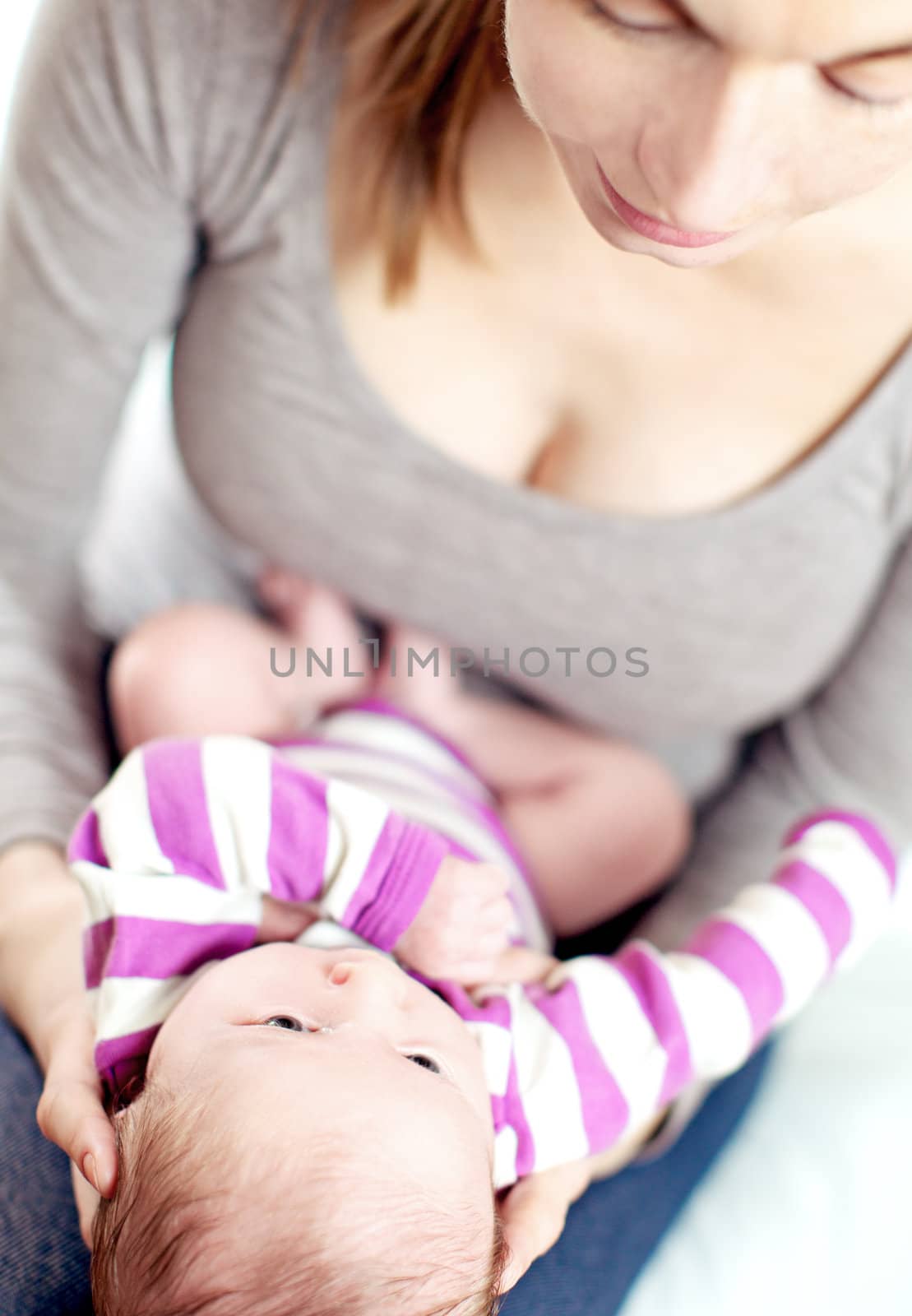 Mum and baby share a tender moment as she cradles it on her lap and they look into each others eyes with love