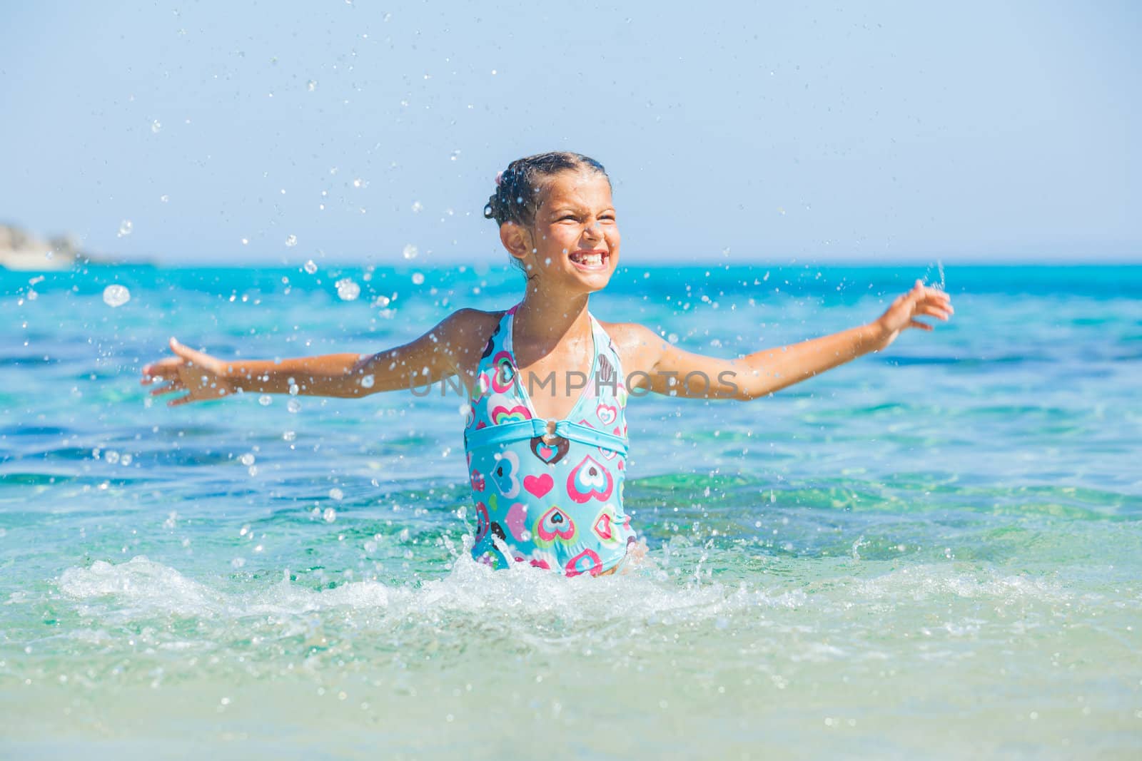 Young girl playing in the wave with spray