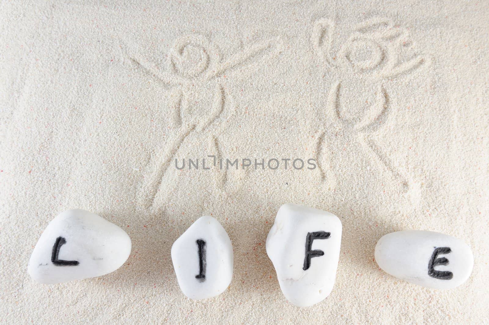 Life word on group of stones with sand as background