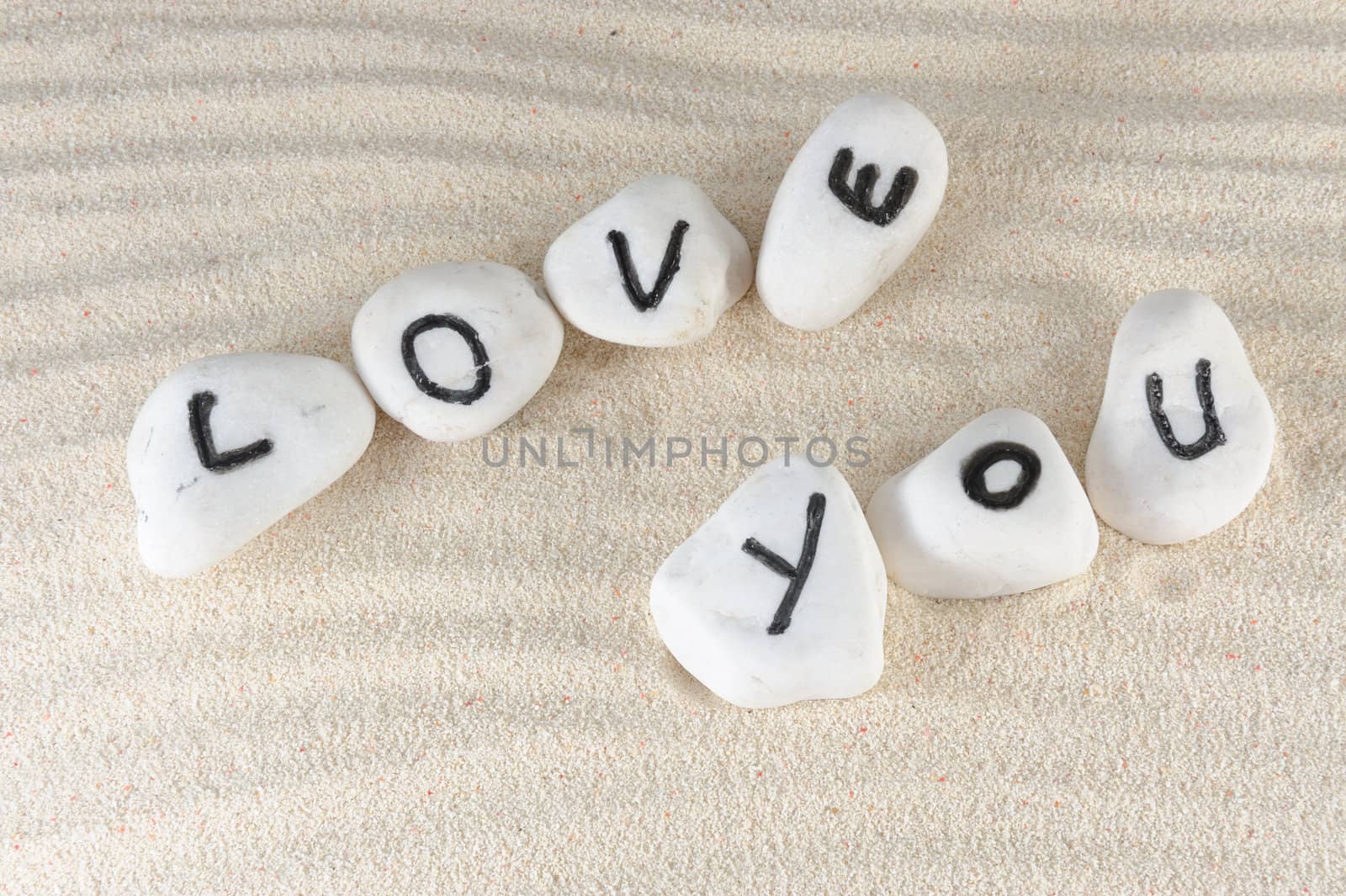 Love you words on group of stones with sand as background
