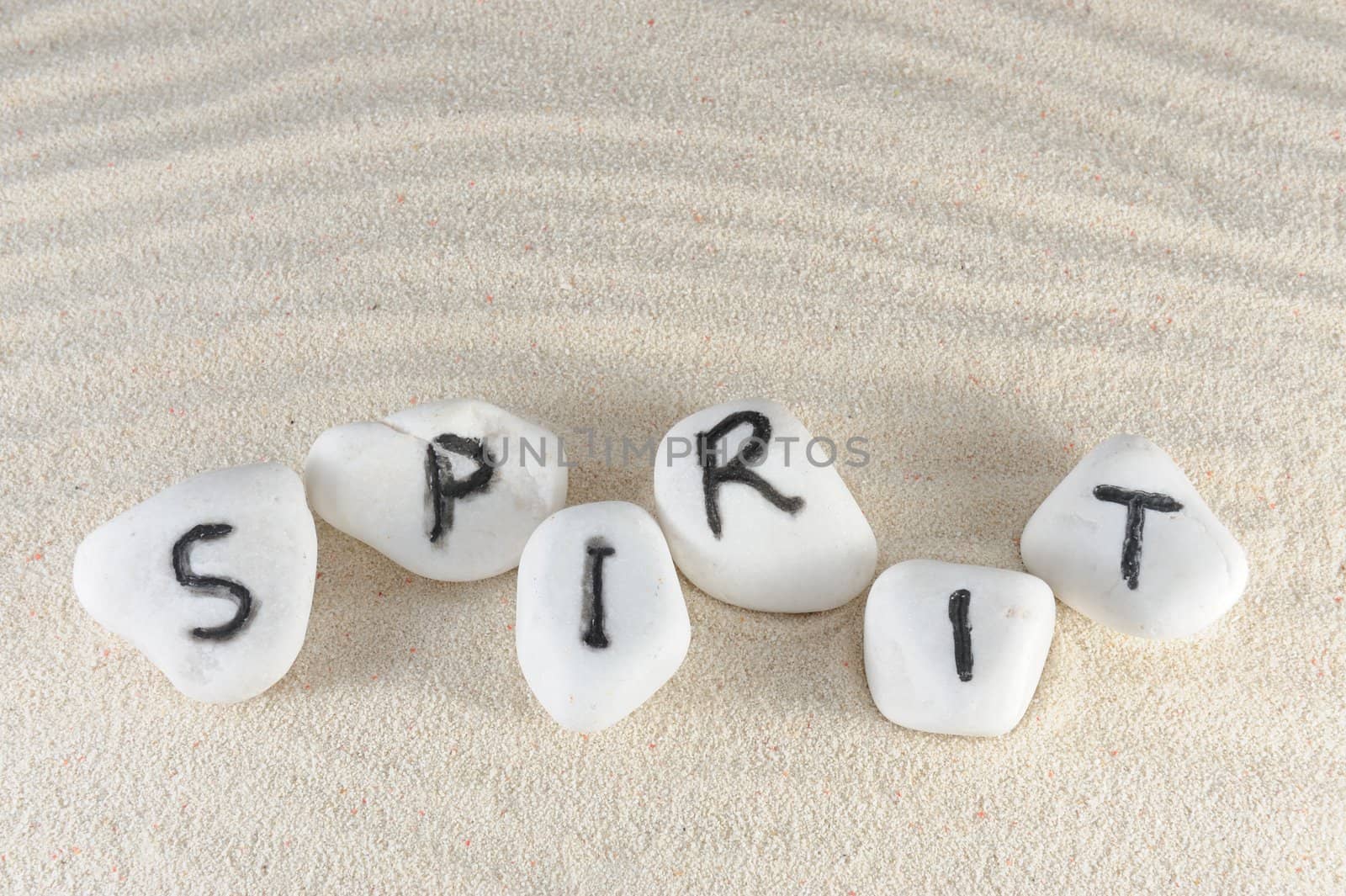 Spirit word on group of stones with sand background