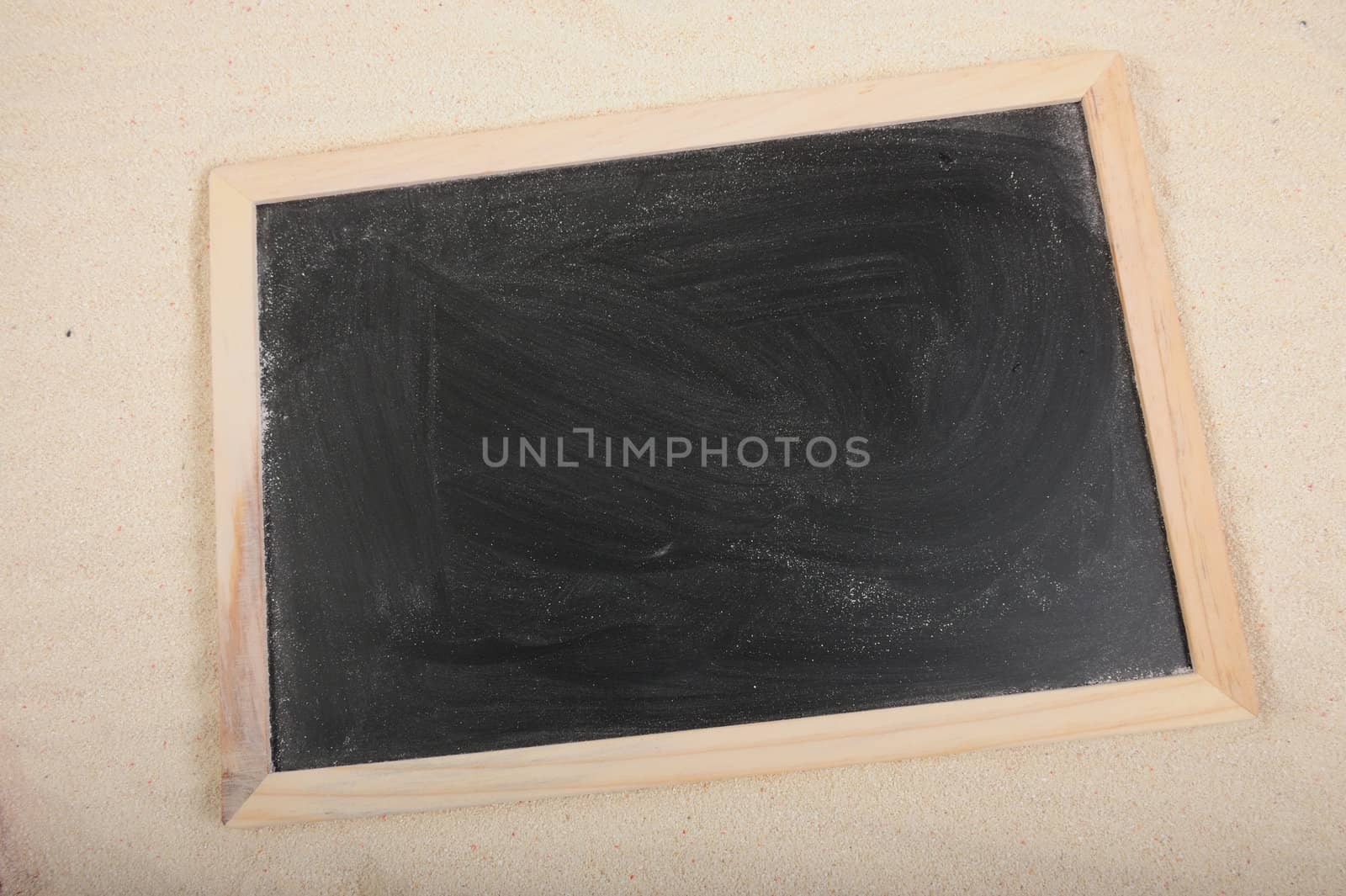 Blackboard with wooden frame border on the sand