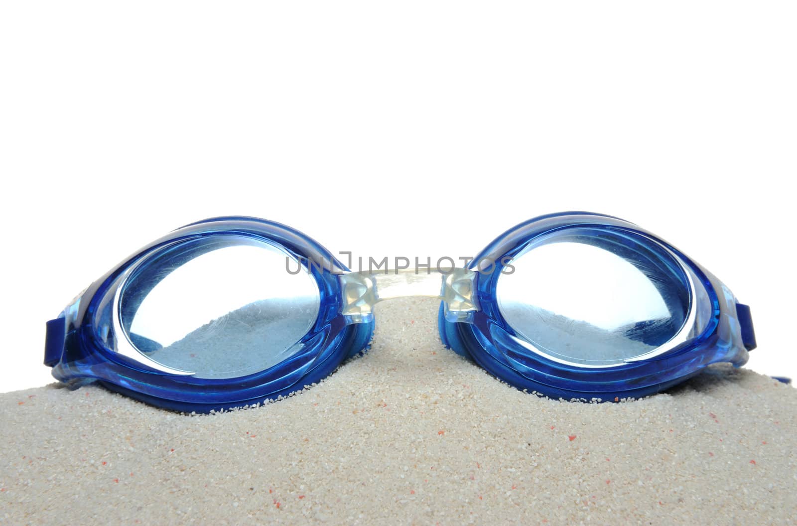 Swimming goggles on the sand isolated on white background