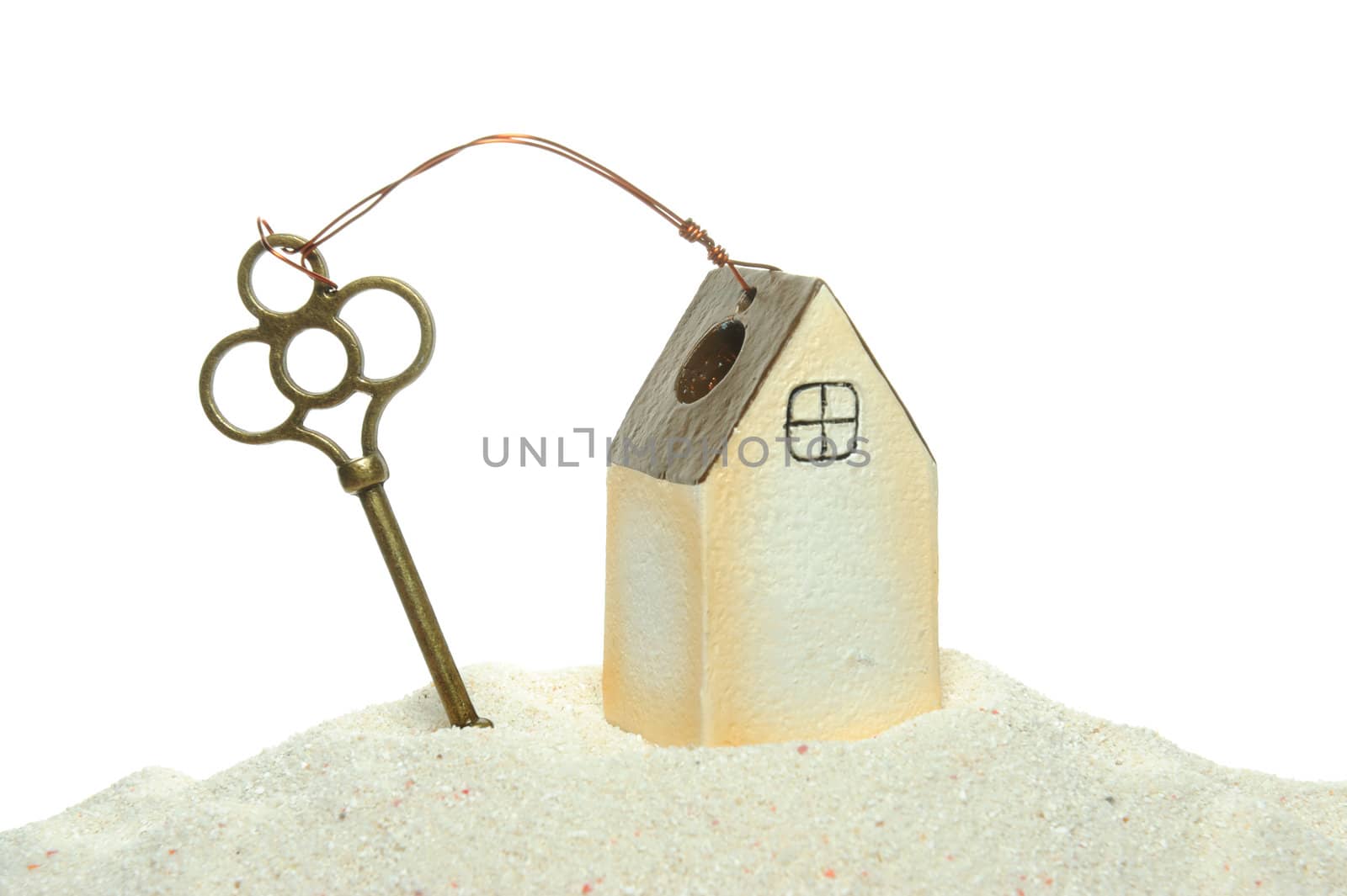 key and house model on the sand isolated on white