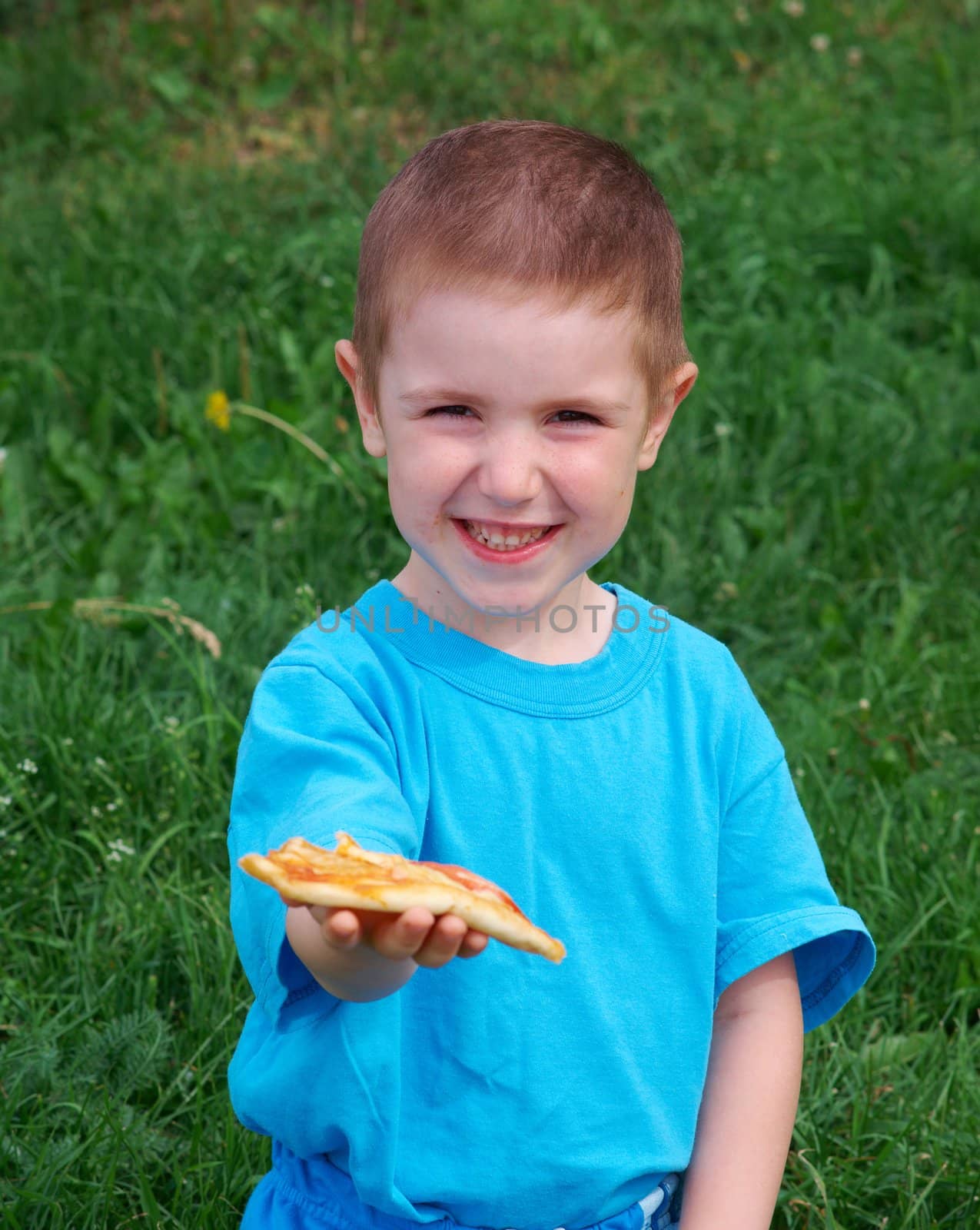 Picnic on the grass. boy   have a dinner with pizza on the meadow .