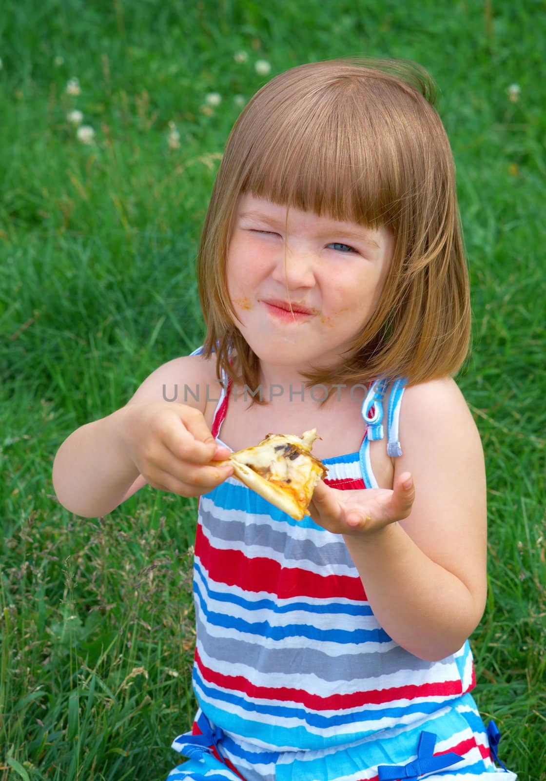 Picnic on the grass. small girl  have a dinner with pizza on the meadow .