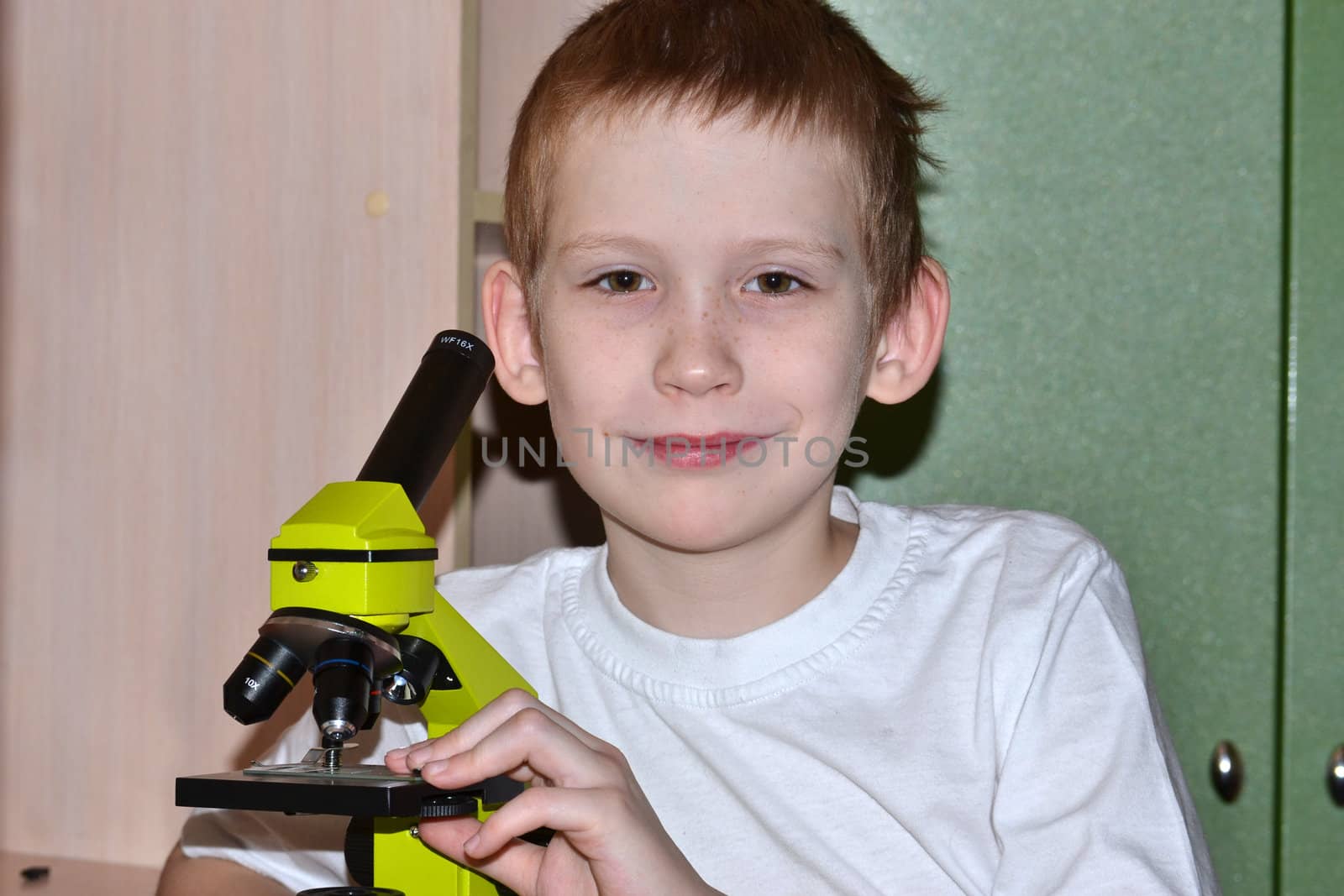 The boy looks in a microscope