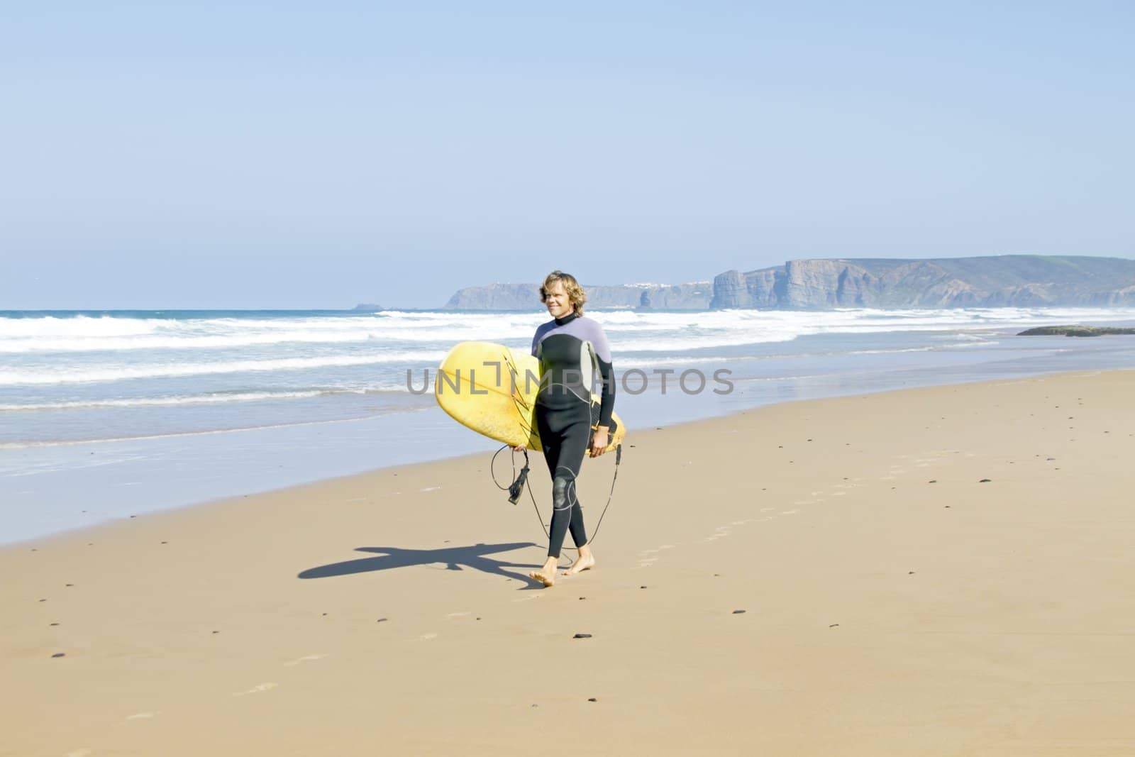 Surfer with his surfboard at the beach by devy