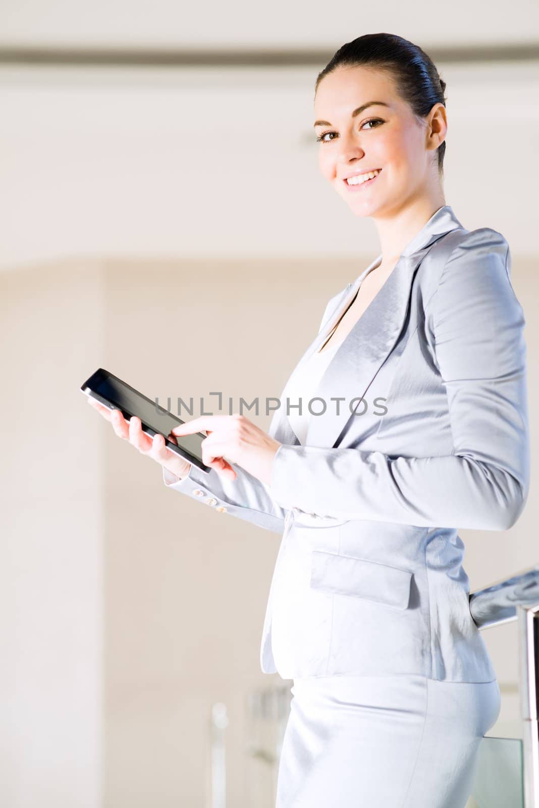 Portrait of a business woman in the tablet at the office, turned around and looking at the camera