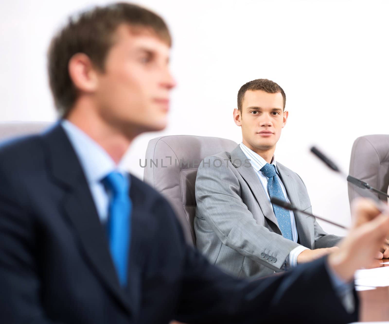 Portrait of a businessman, said into the microphone, in the background colleagues communicate with each other