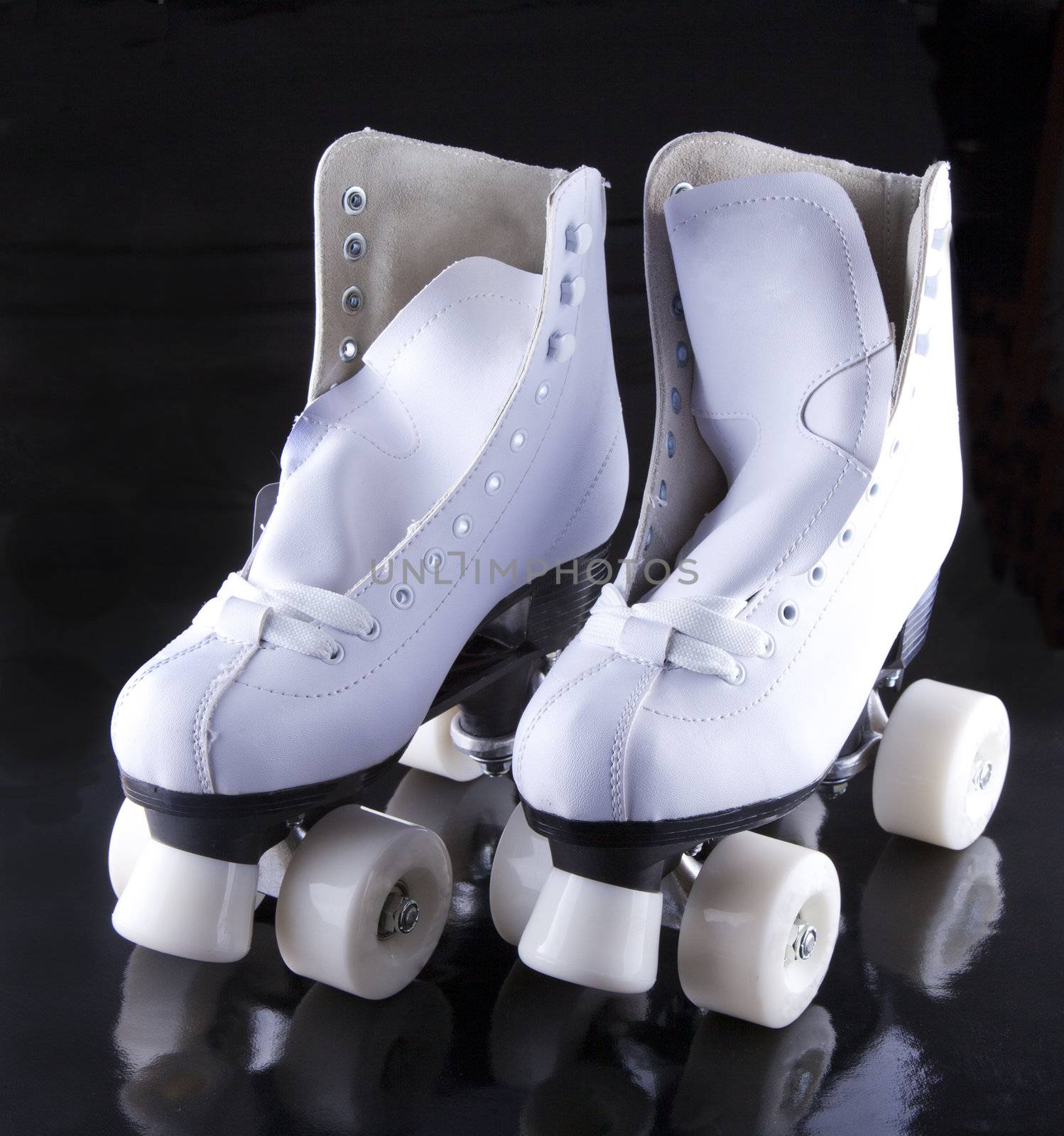 A pair of white roller skates over black background