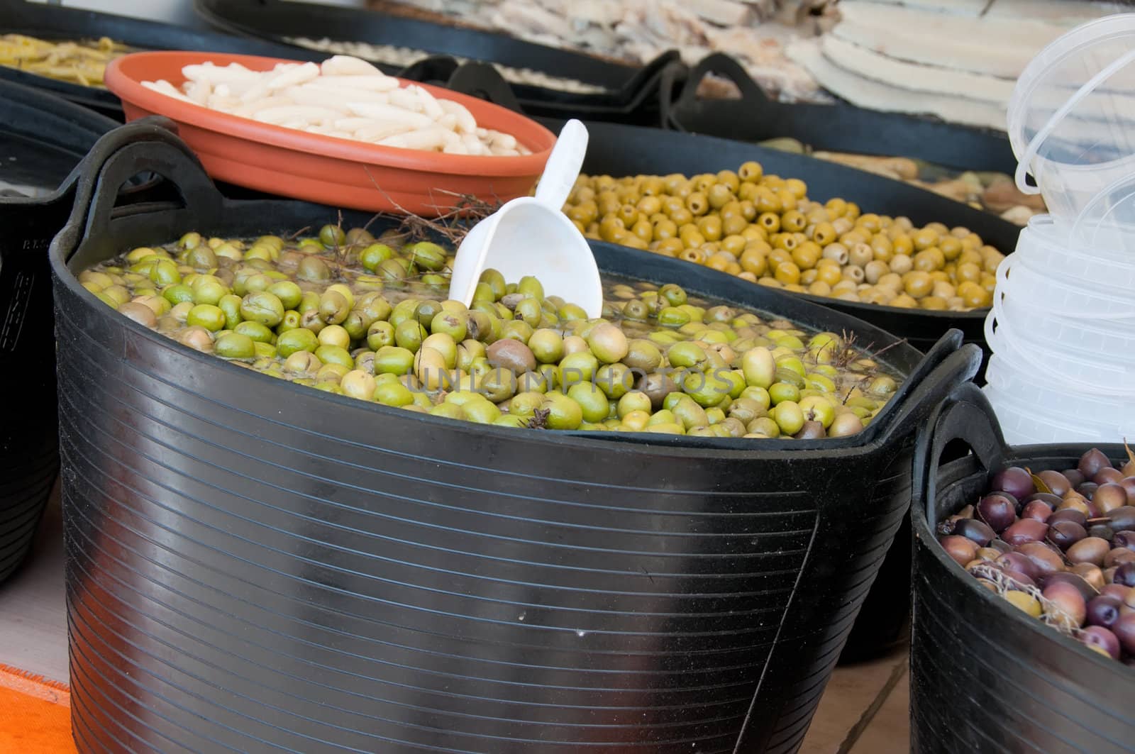 Different sorts of olives in big black barrels