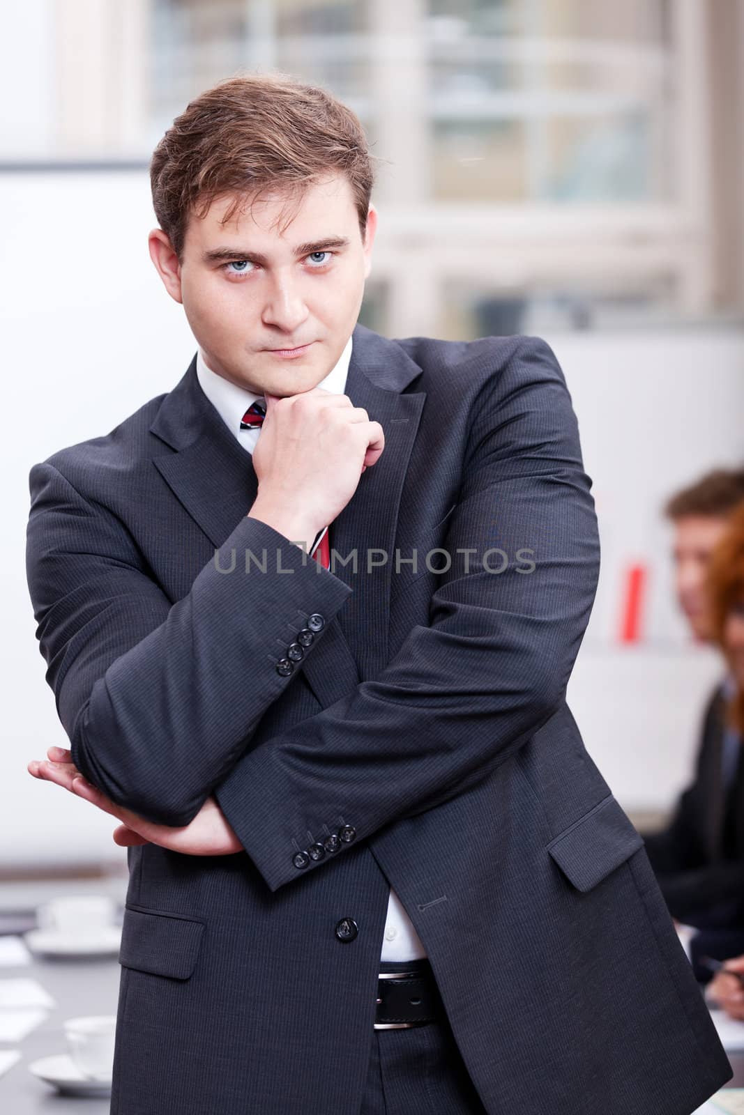 successful business smiling man portrait at office with team in background