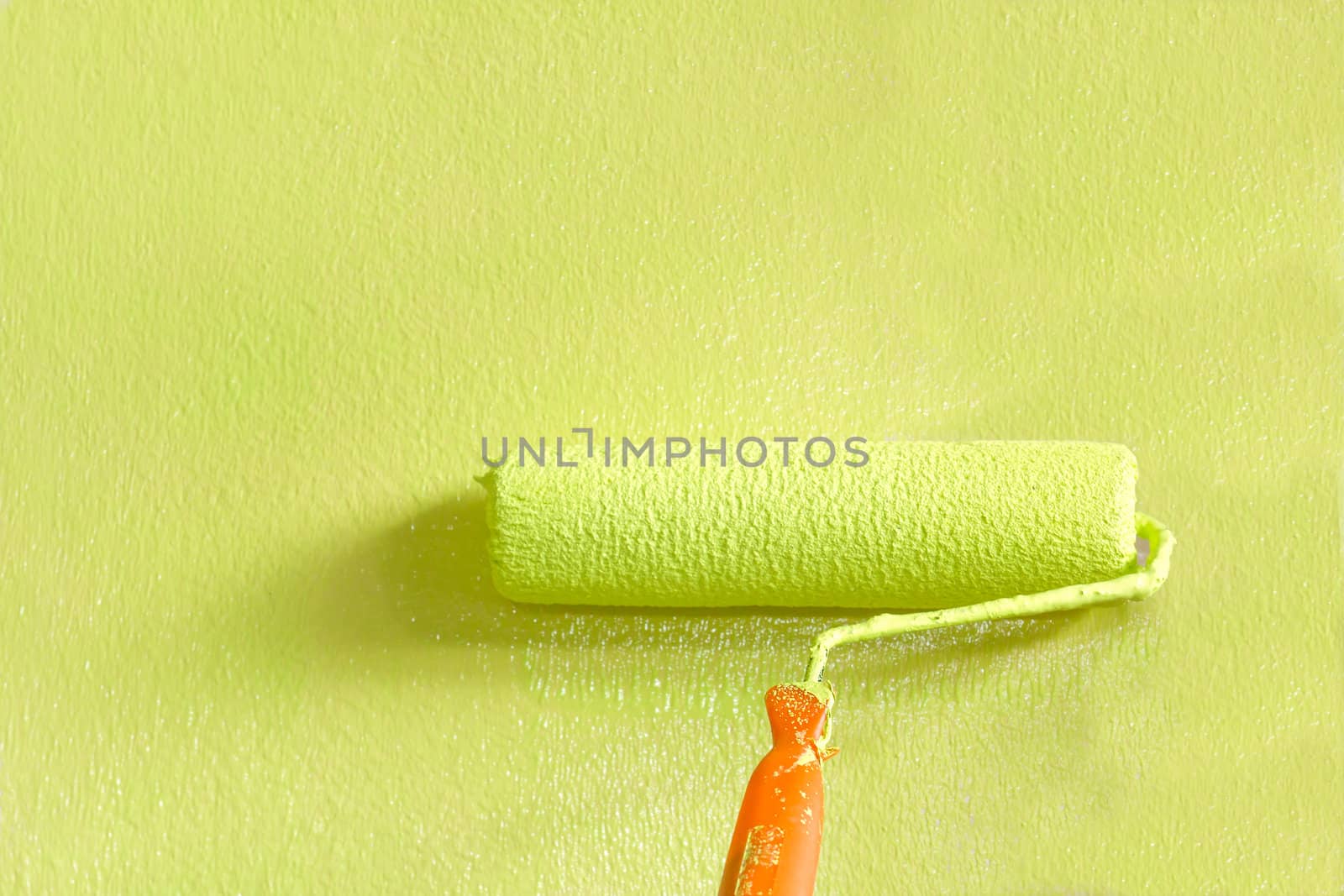 Wall painter using a paint roller, painting a wall in motion
