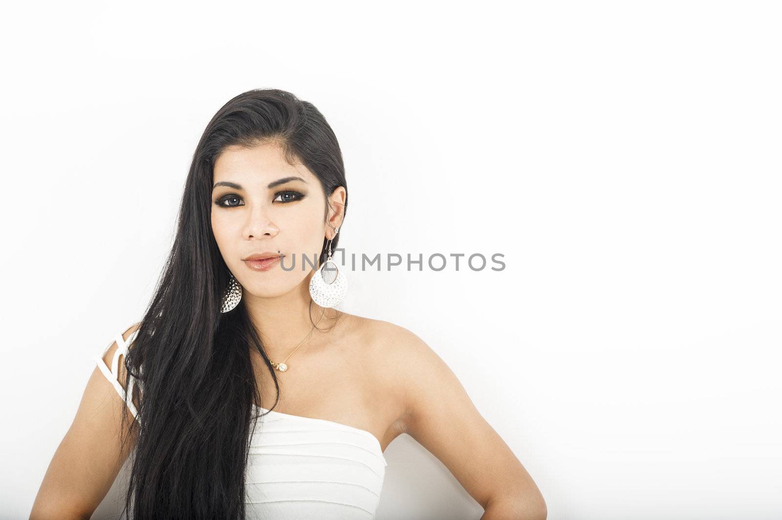 Attractive sophisticated Asian woman in an elegant off the shoulder dress and jewellery, studio portrait with copyspace