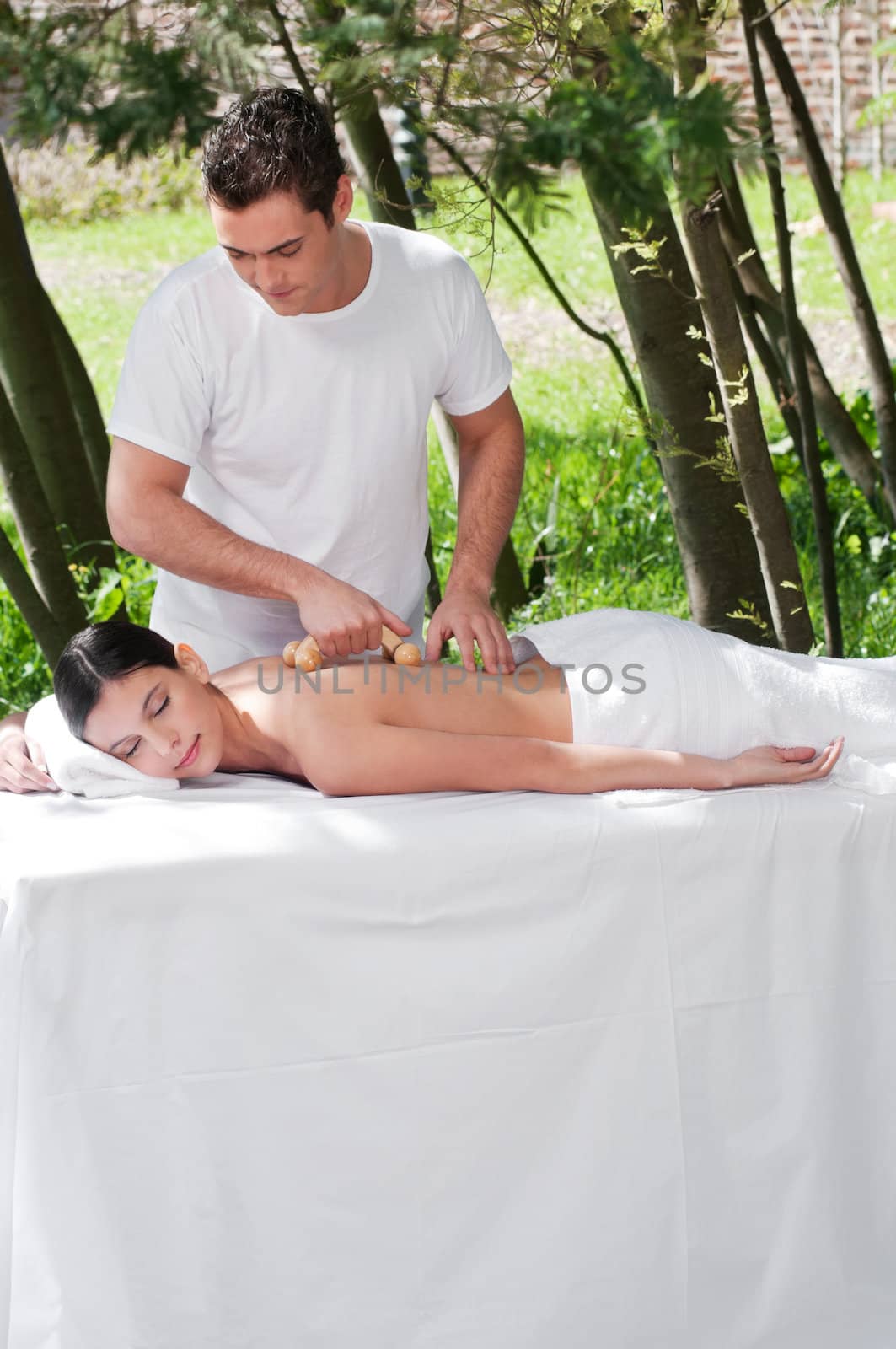 Man giving massage to woman by a wooden massager by leaf