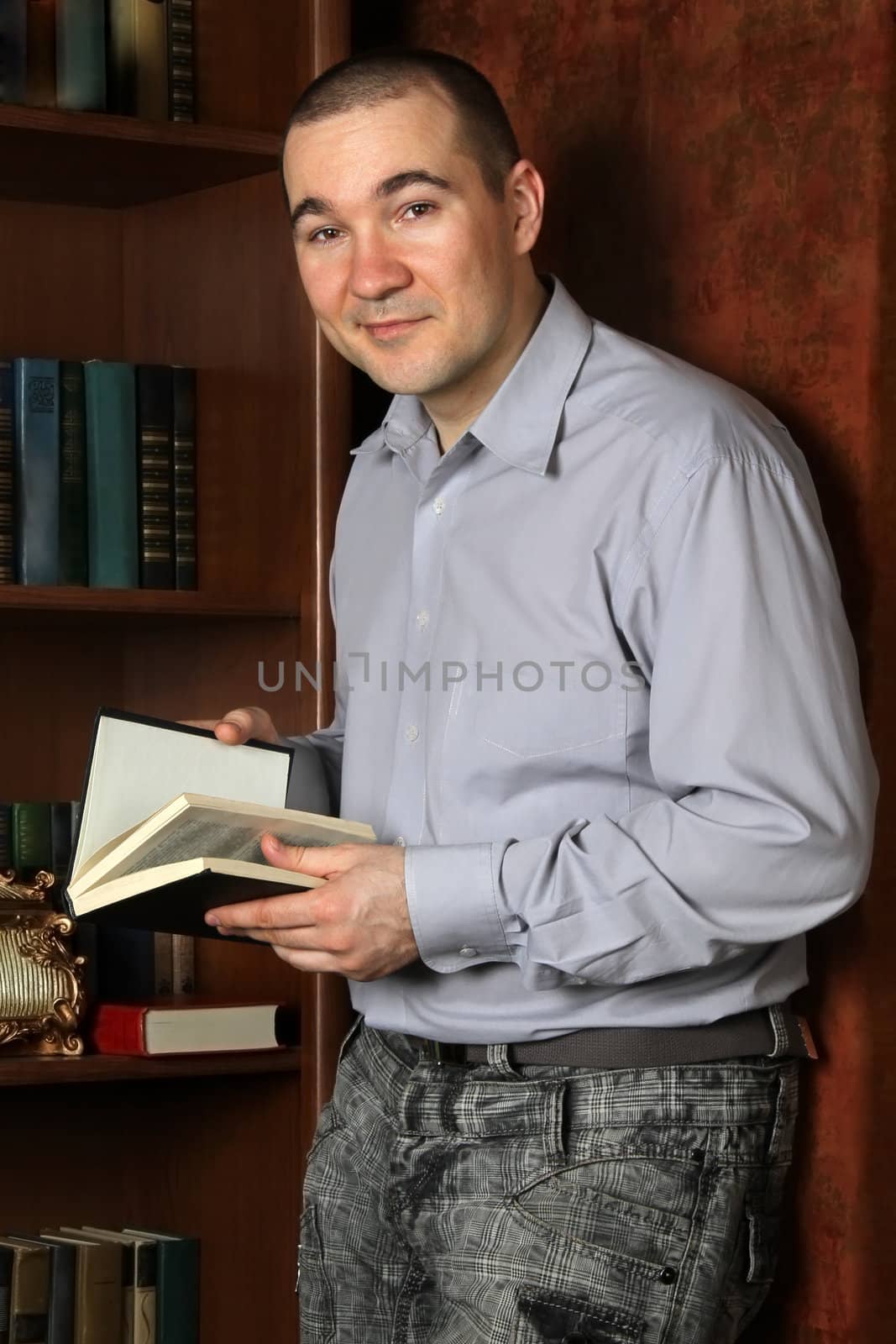 Young man standing with a book (in the interior)