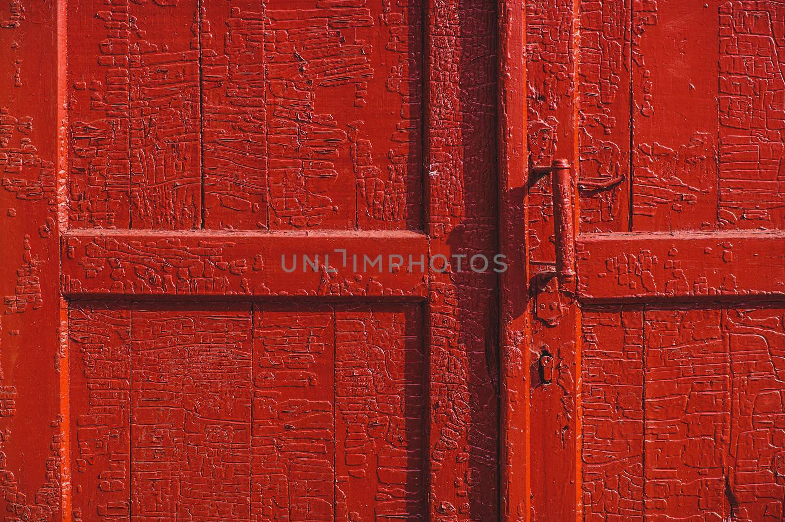 An old wood door with cracked red paint and grunge