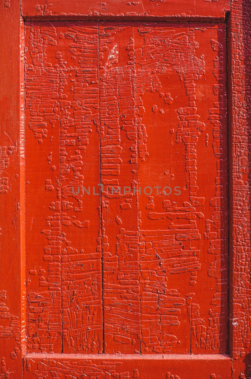 An old wood door panel with cracked red paint and grunge