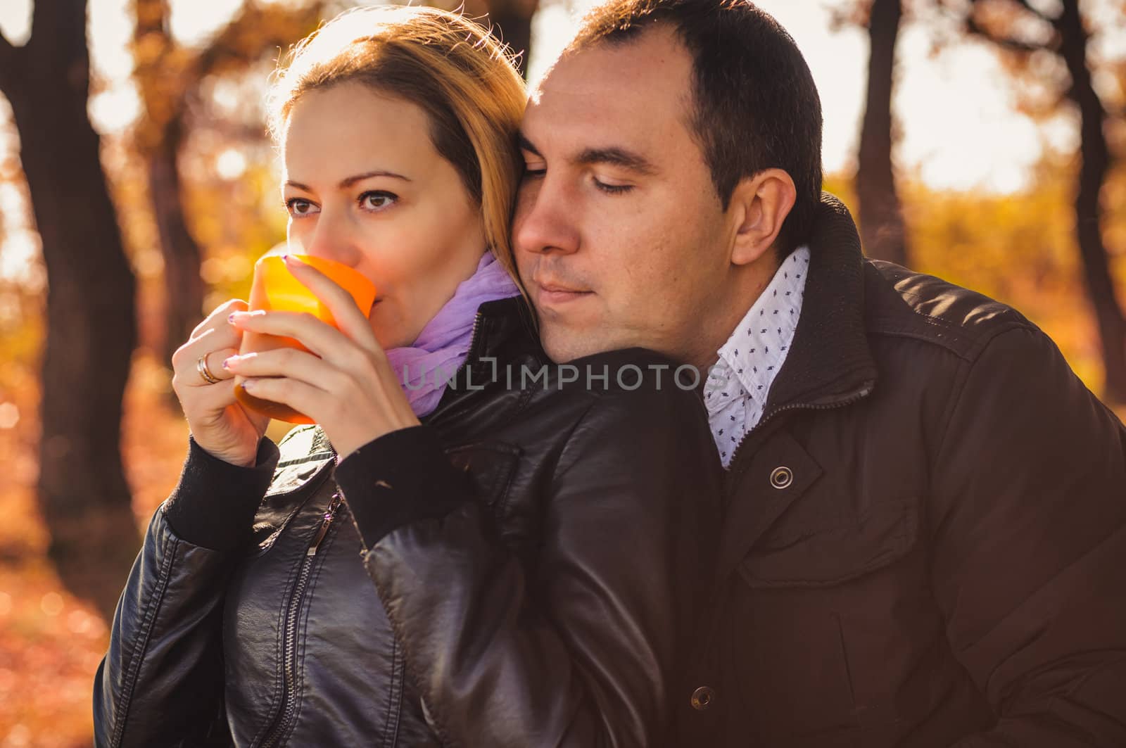 Young family drinking coffee in autumn forest