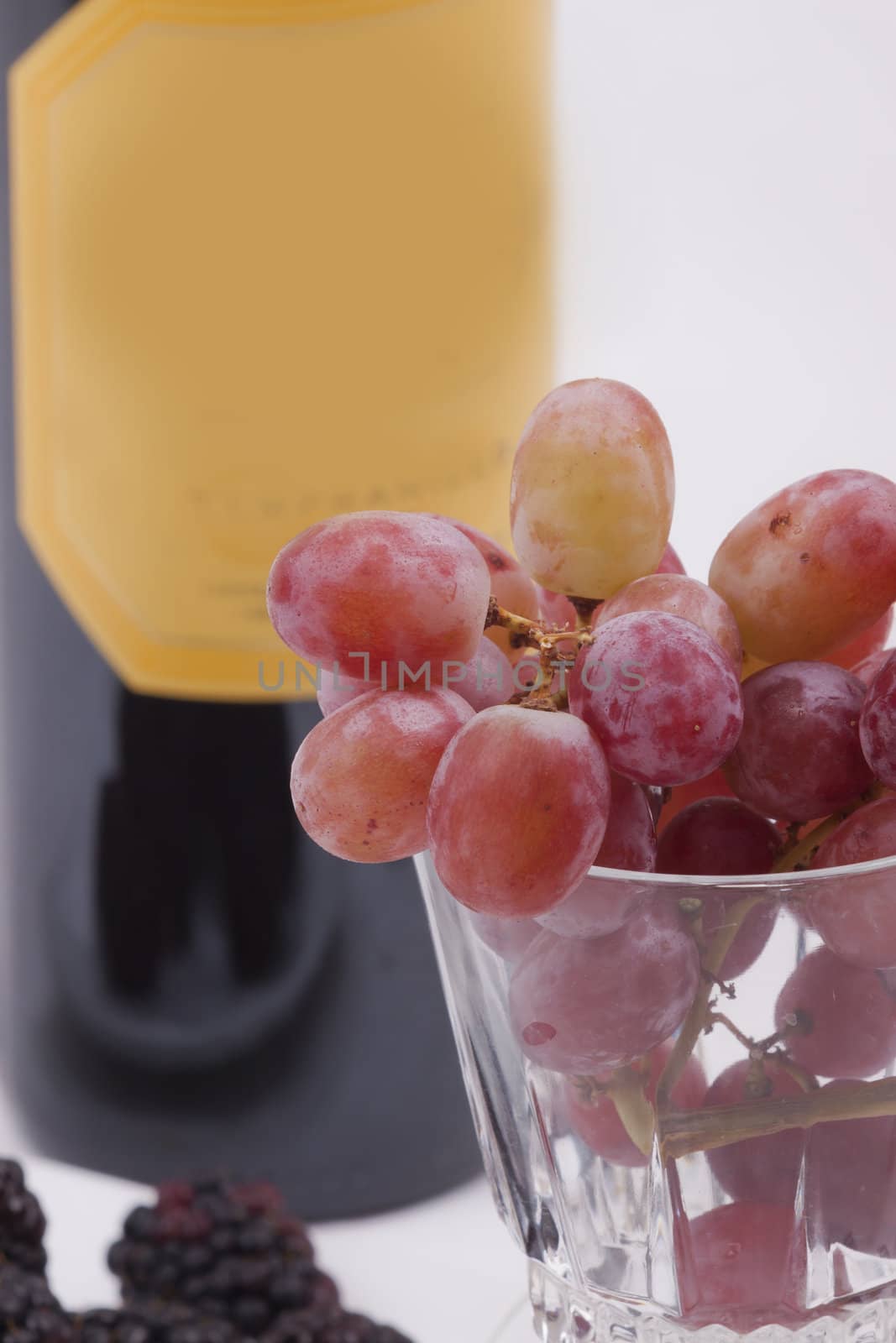 Bottle of red wine, and glass filled with grapes