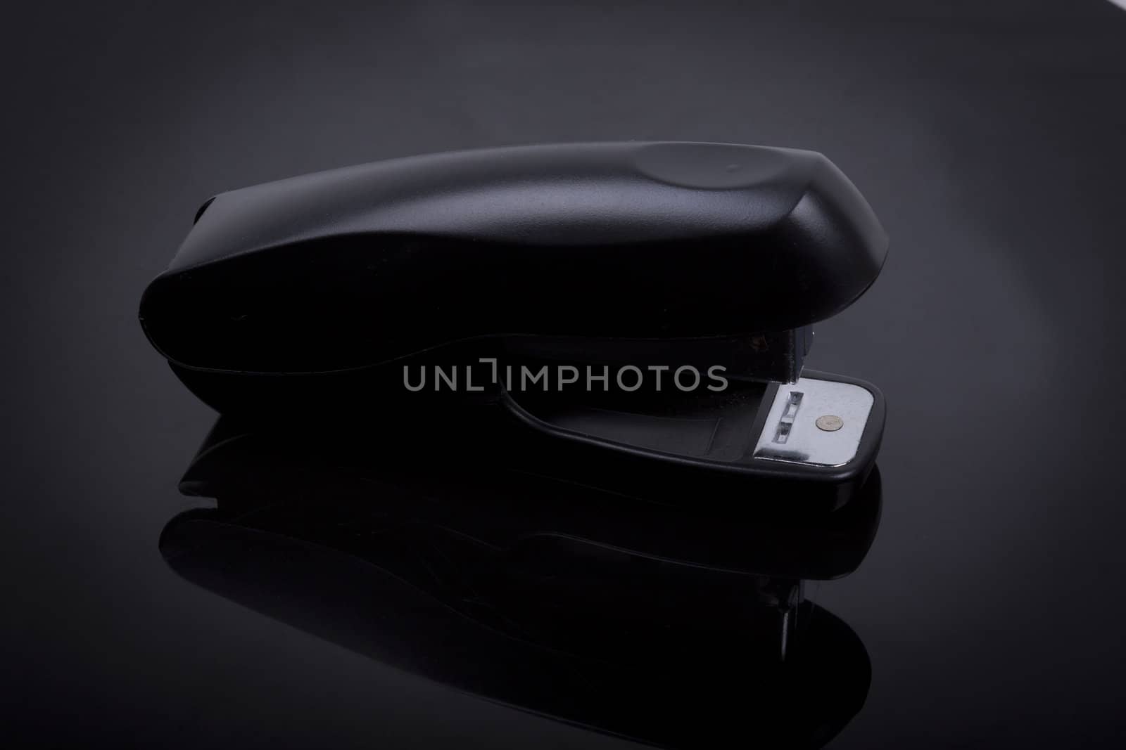 photo  of a stapler on a black shiny background