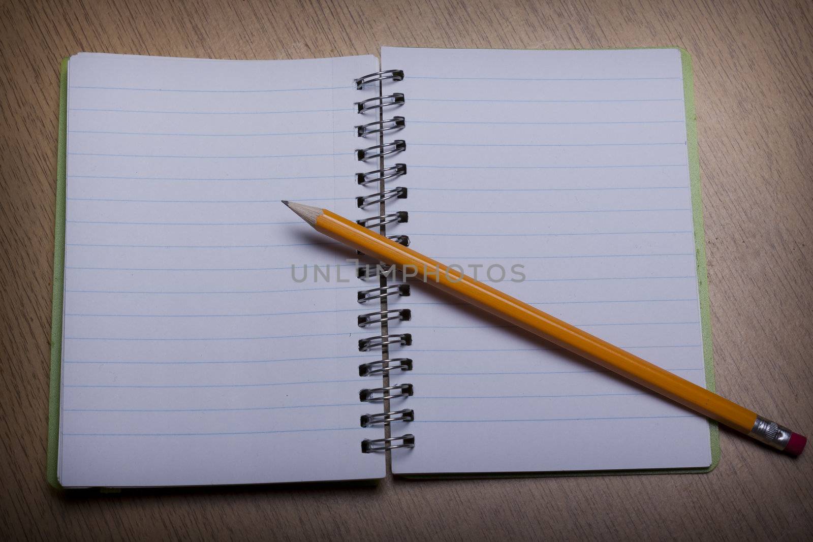 open  notebook on a wooden desk with pencil