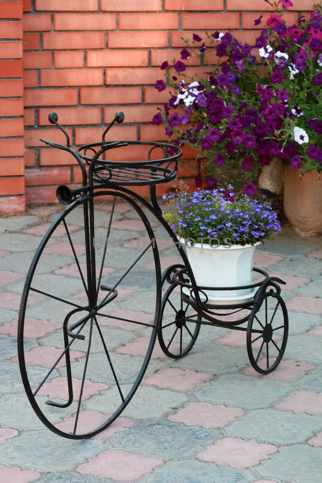 Decorative stand for flowers retro bicycle against a brick wall and park footpath tiles