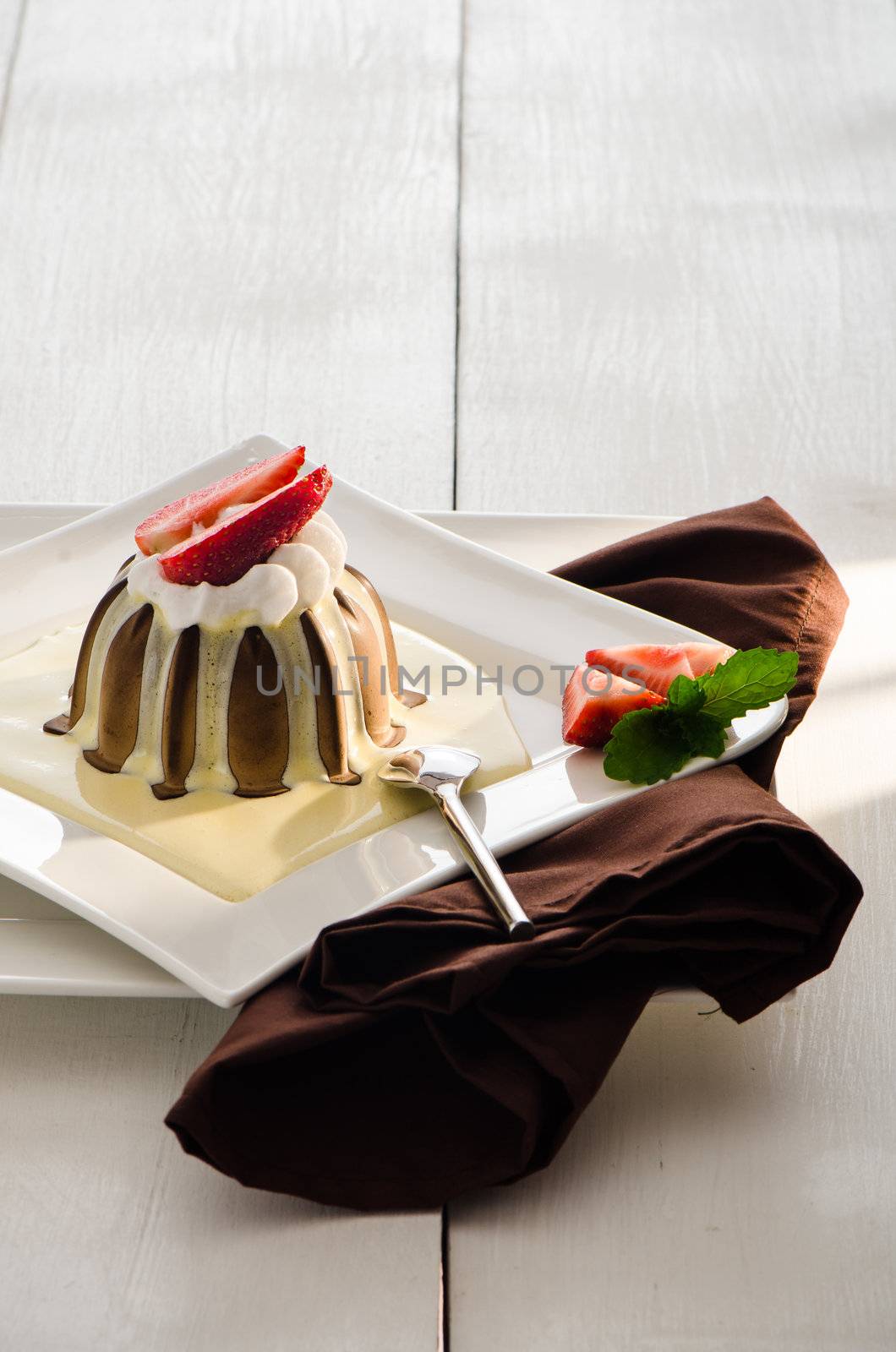 chocolate pudding with vanilla sauce strawberry and mint on white plate