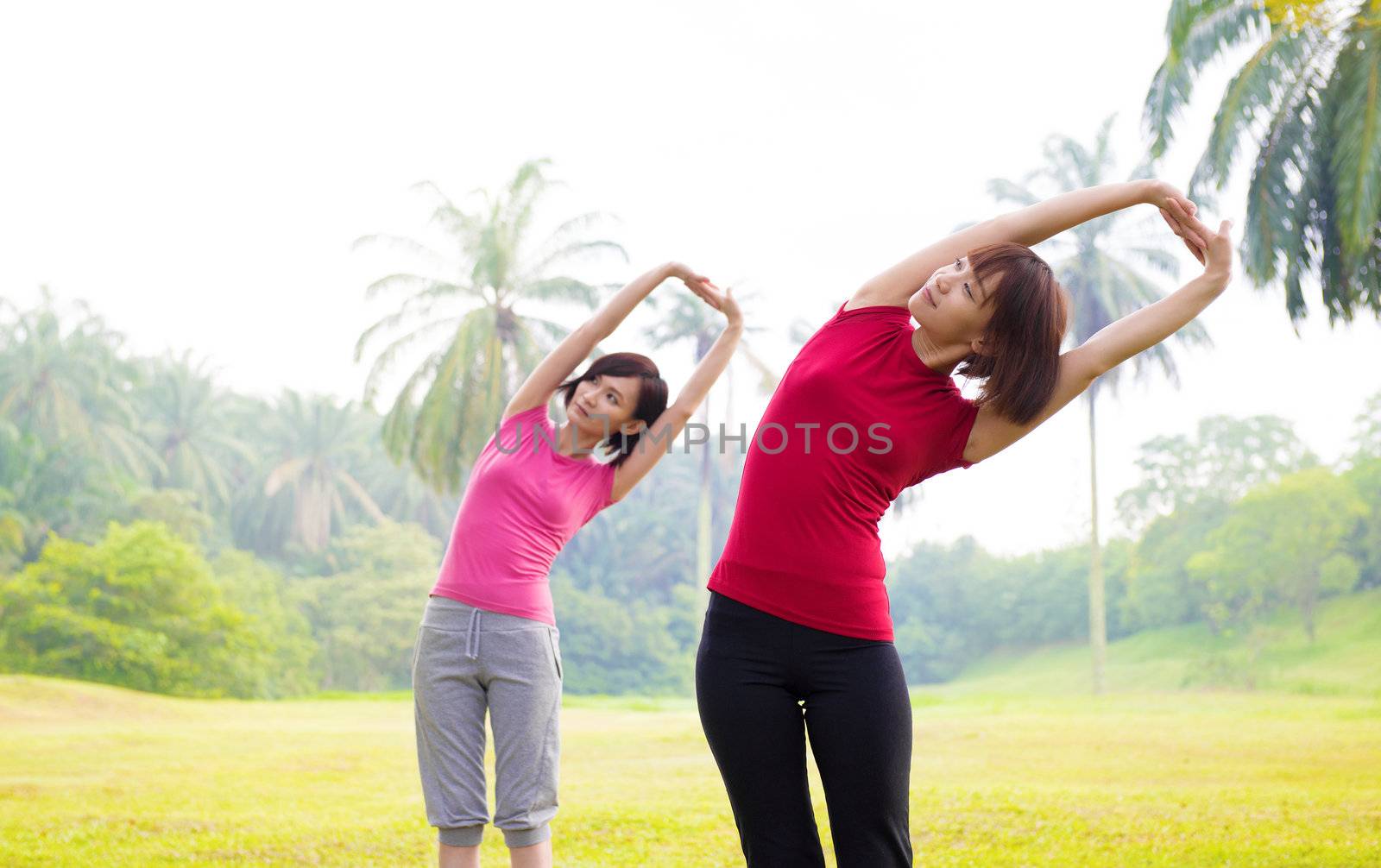 Two Asian girls stretching outdoor green park