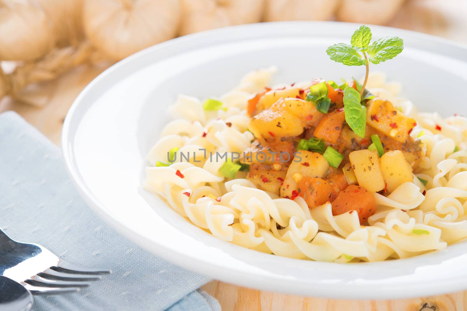 Pasta fusilli with potatoes, carrot and tomatoes on the kitchen table