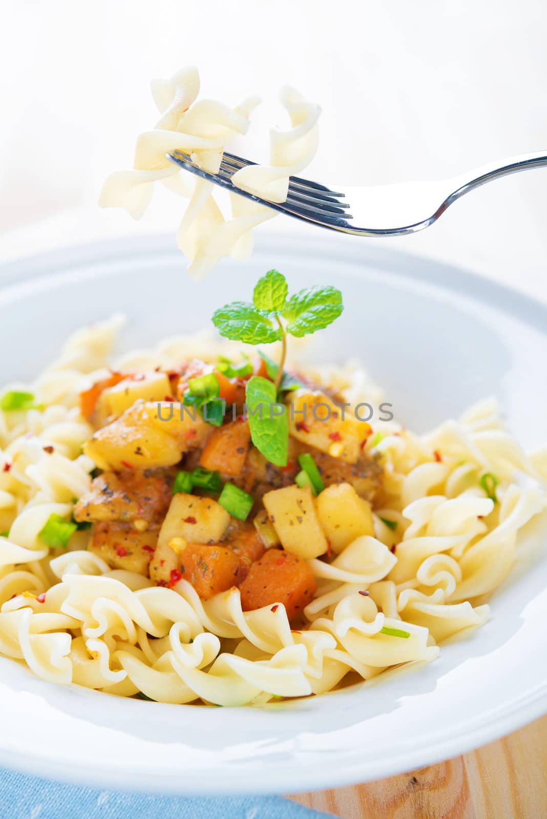 Delicious pasta fusilli with potatoes, carrot and tomatoes on the kitchen table