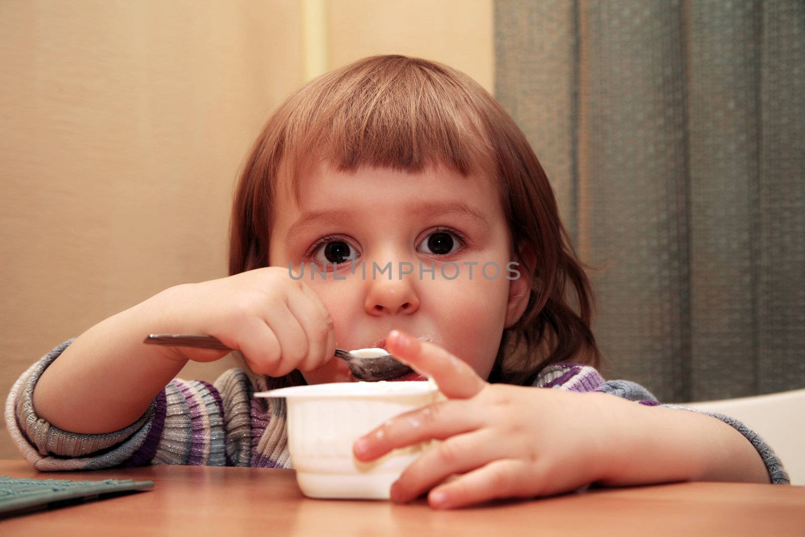 The little girl eats yoghurt of at home