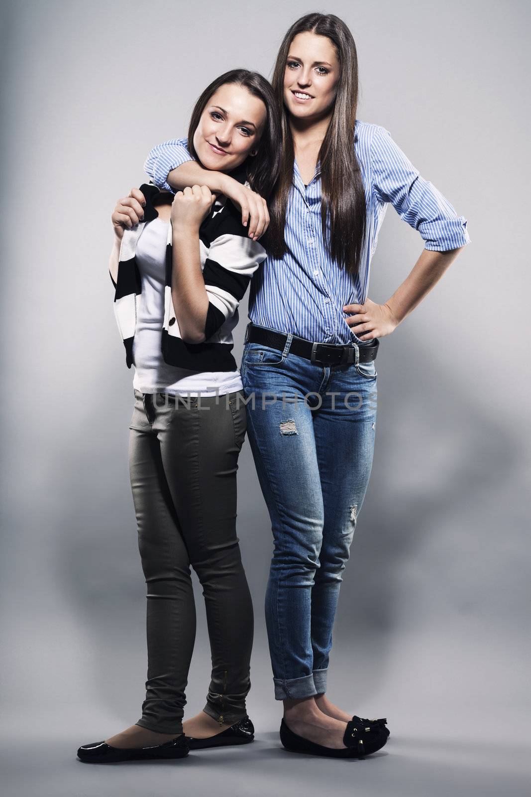 teenager hugging her sister on gray background