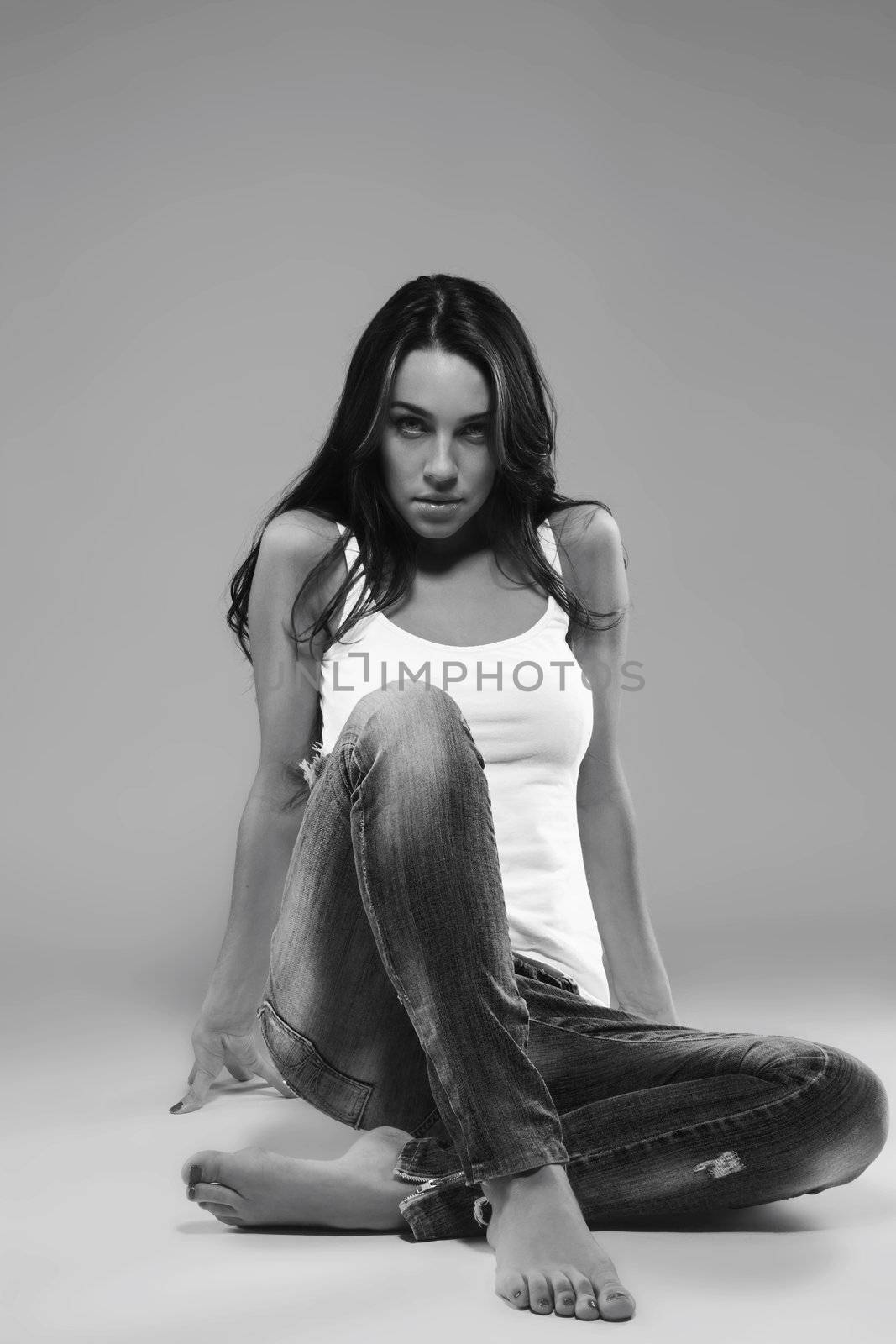 gorgeous woman wearing blue jeans sitting on the floor in black and white