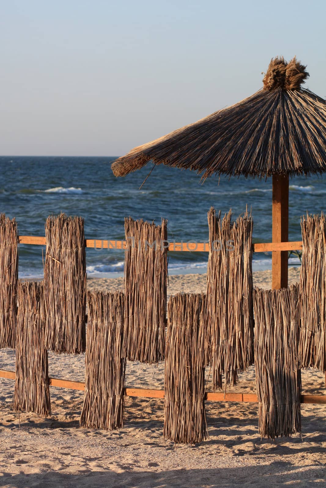 Beach fence and shed mushroom of reeds on the beach at sea