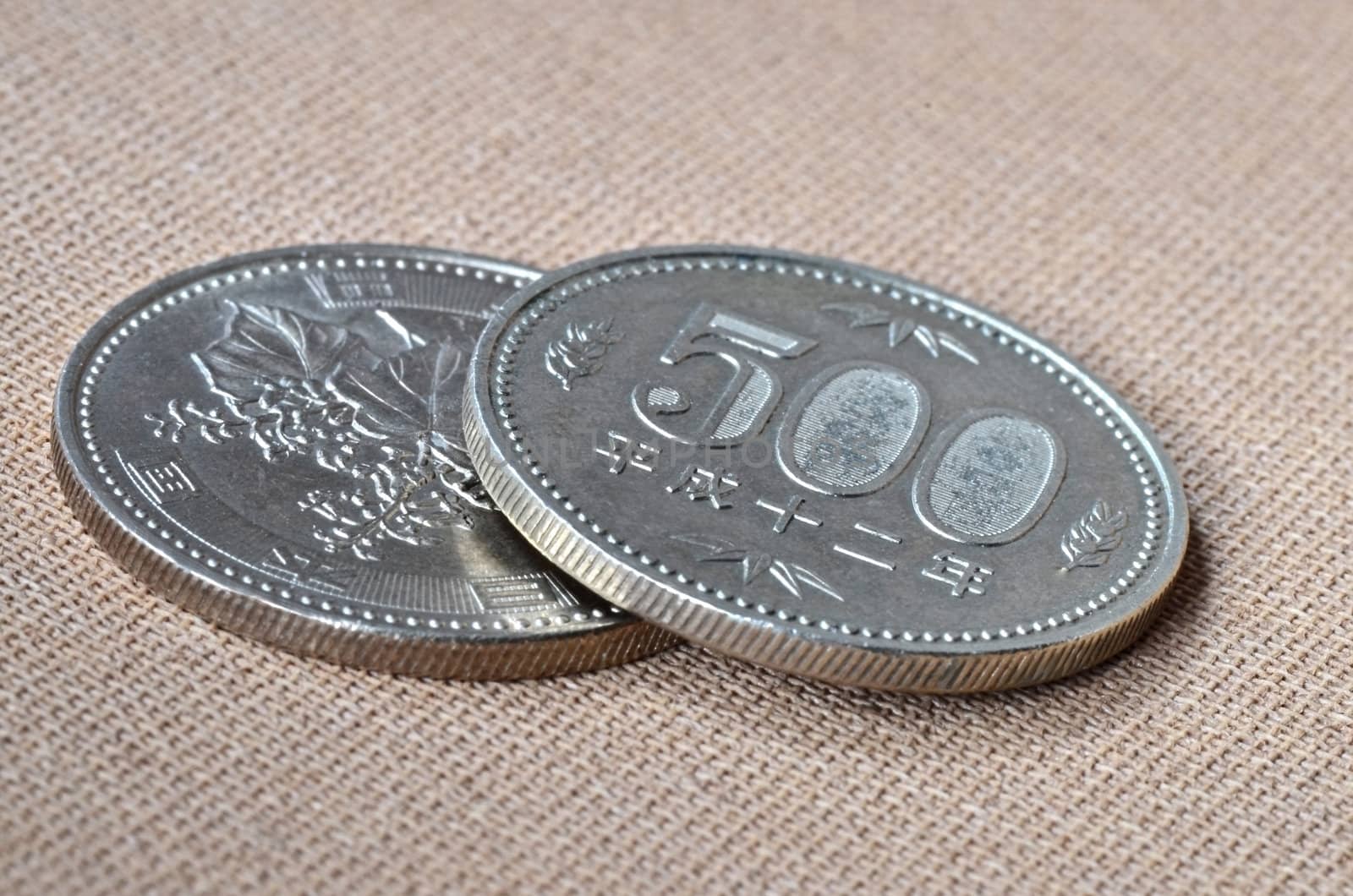 Two 500 japanese Yen coins on oriental beige fabric as background