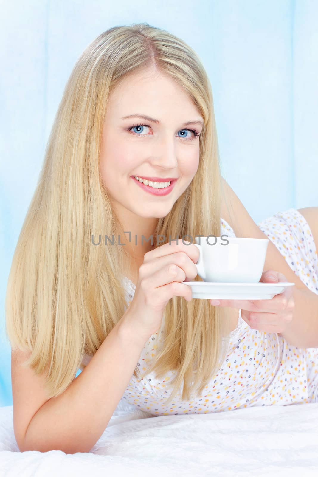 Pretty blond woman drinking coffee in bed