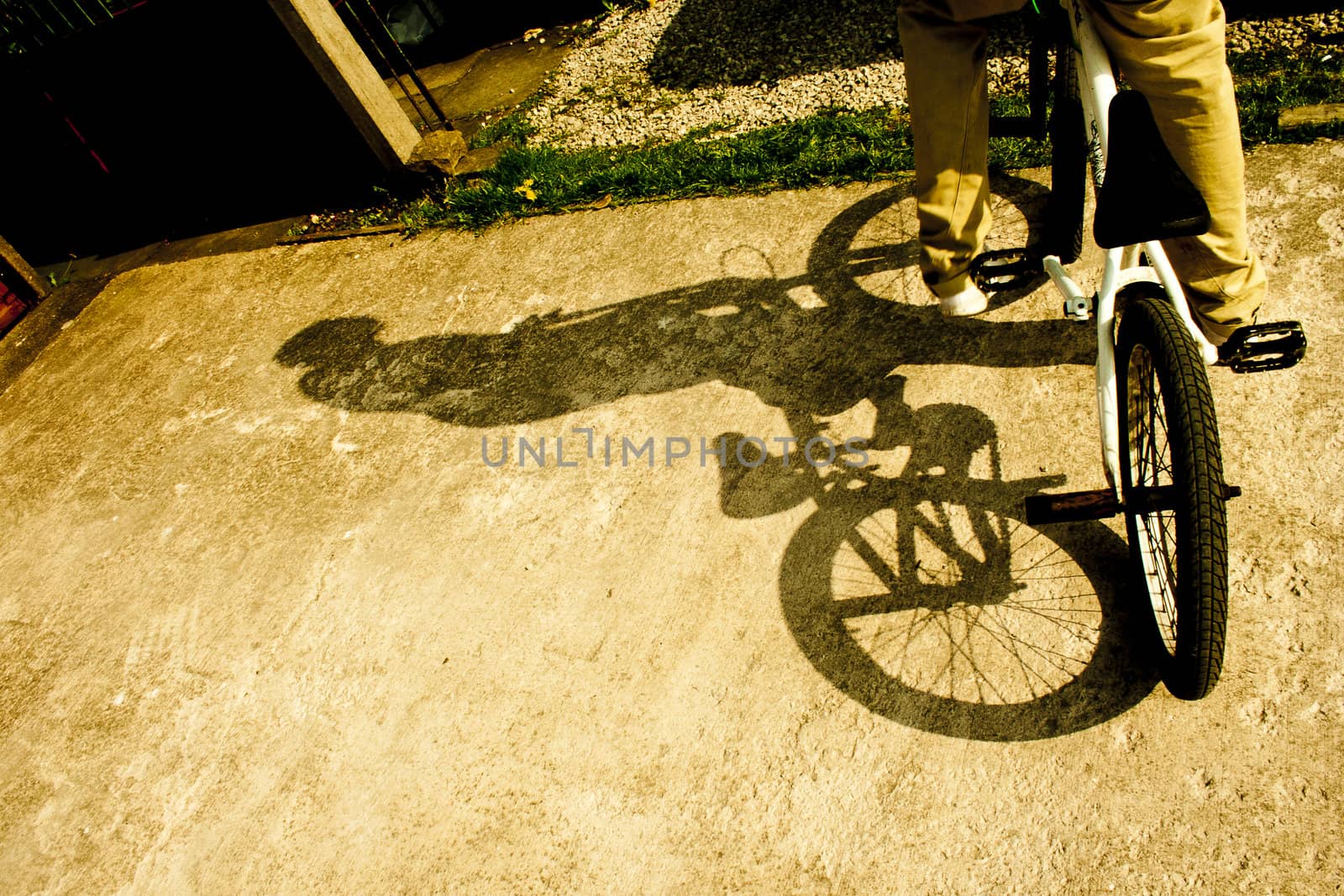 A man sitting on a BMX bike with a shadow cast across a concrete