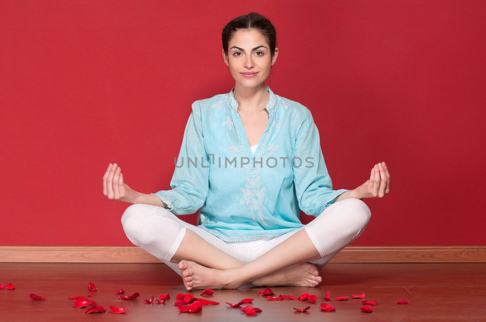 Portrait of young beautiful female practicing yoga with rose petals on floor