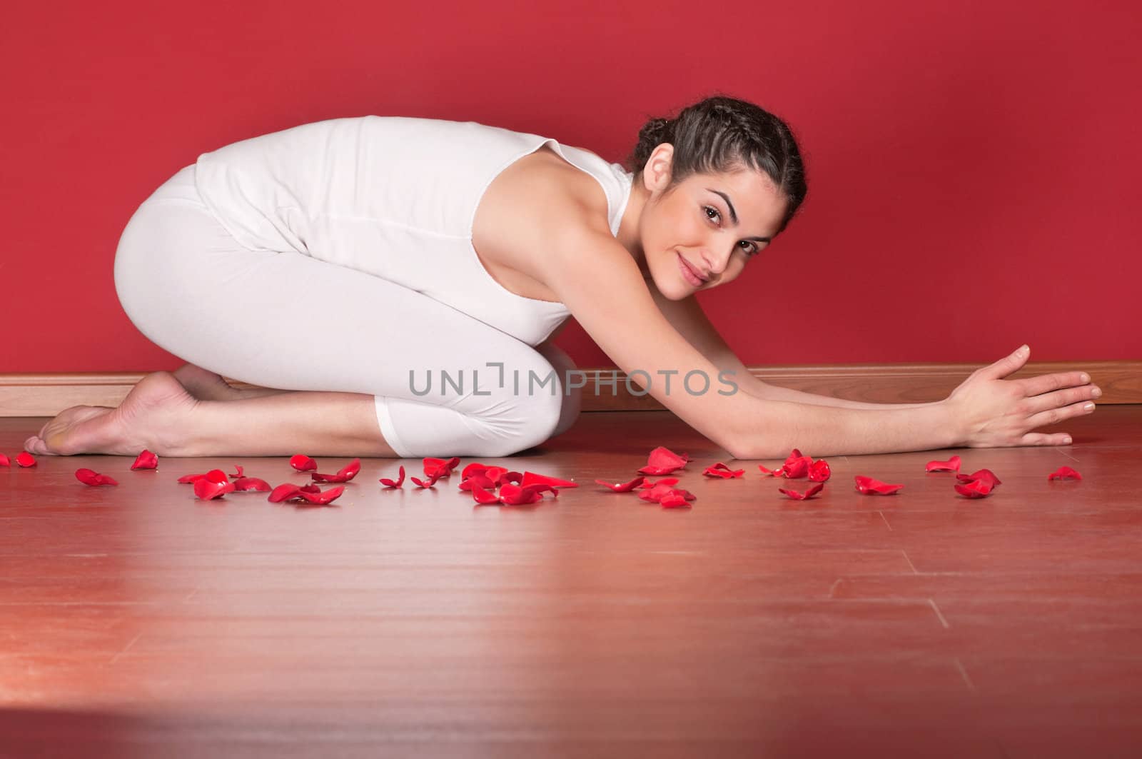 Portrait of a beautiful young woman in a yoga pose with rose petals around