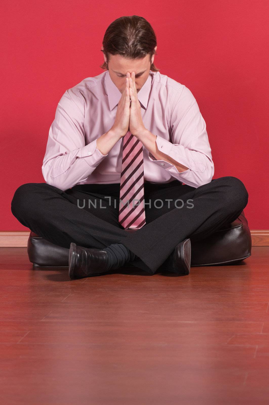 Business executive sitting on the floor with hand clasped