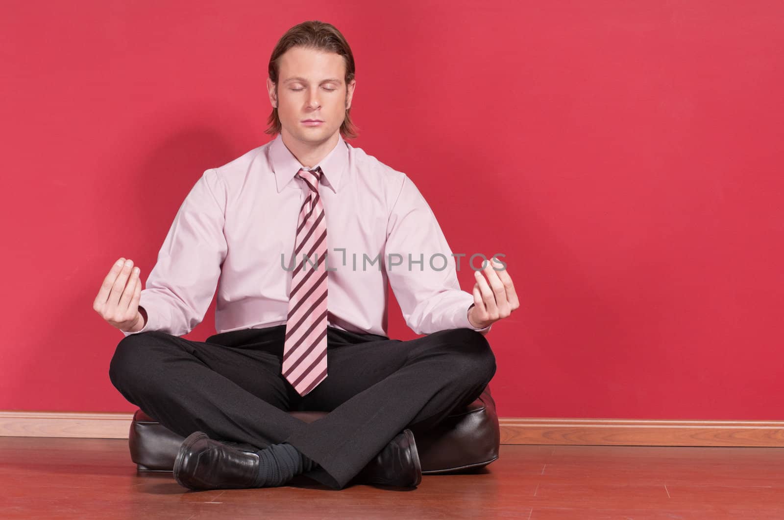 Businessman meditating in yoga lotus pose on floor
