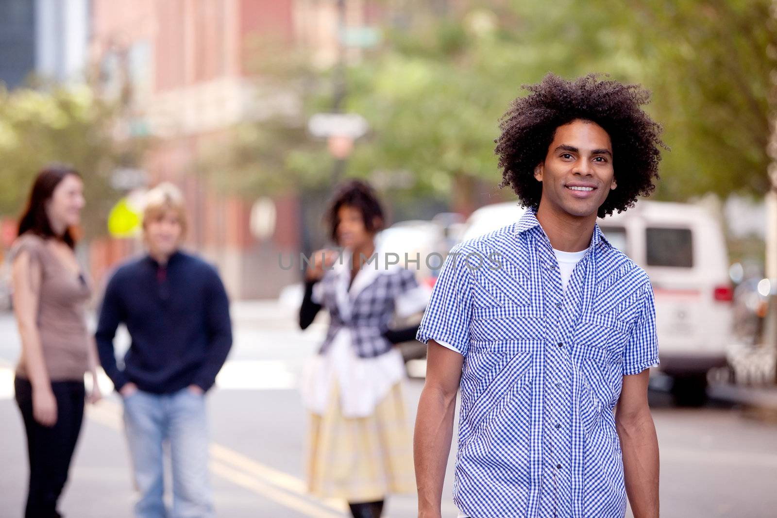 A young male in a city setting with friends in the background