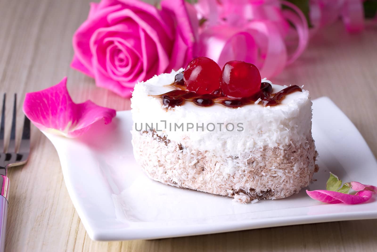 Celebratory cake with cherries on a background of pink roses