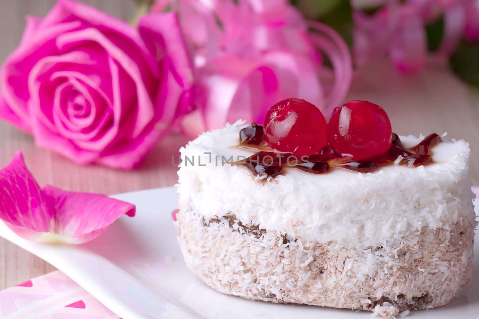 Celebratory cake with cherries on a background of pink roses