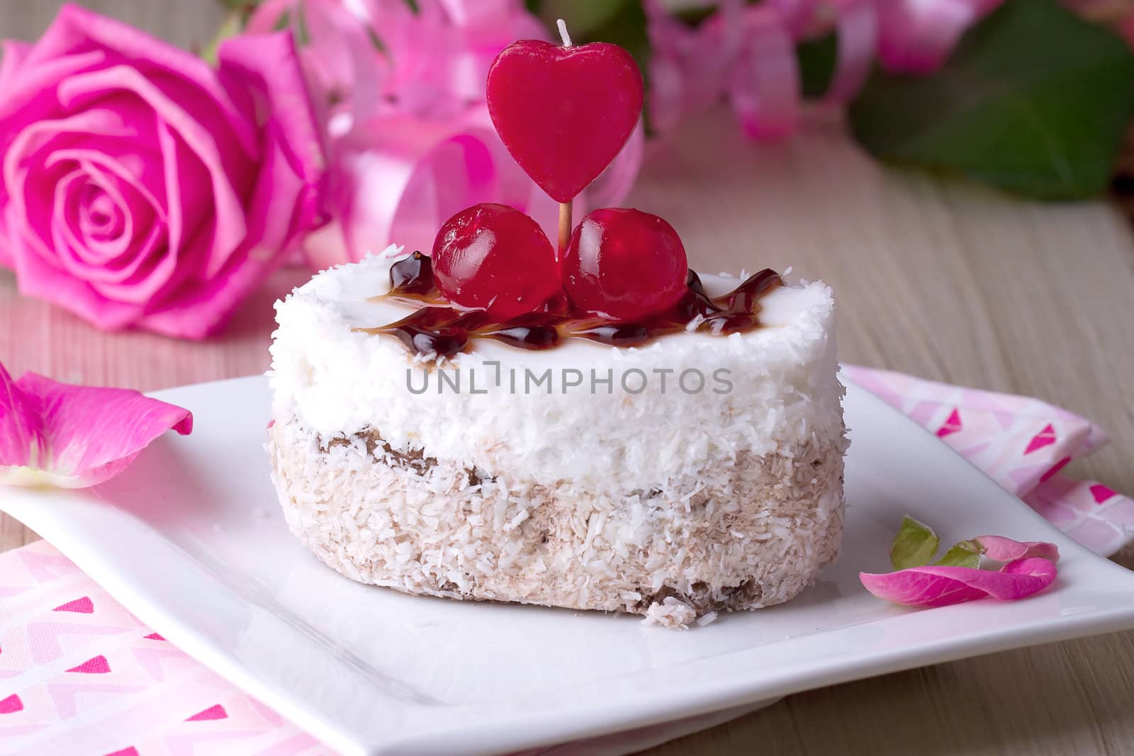 Celebratory cake with cherries on a background of pink roses