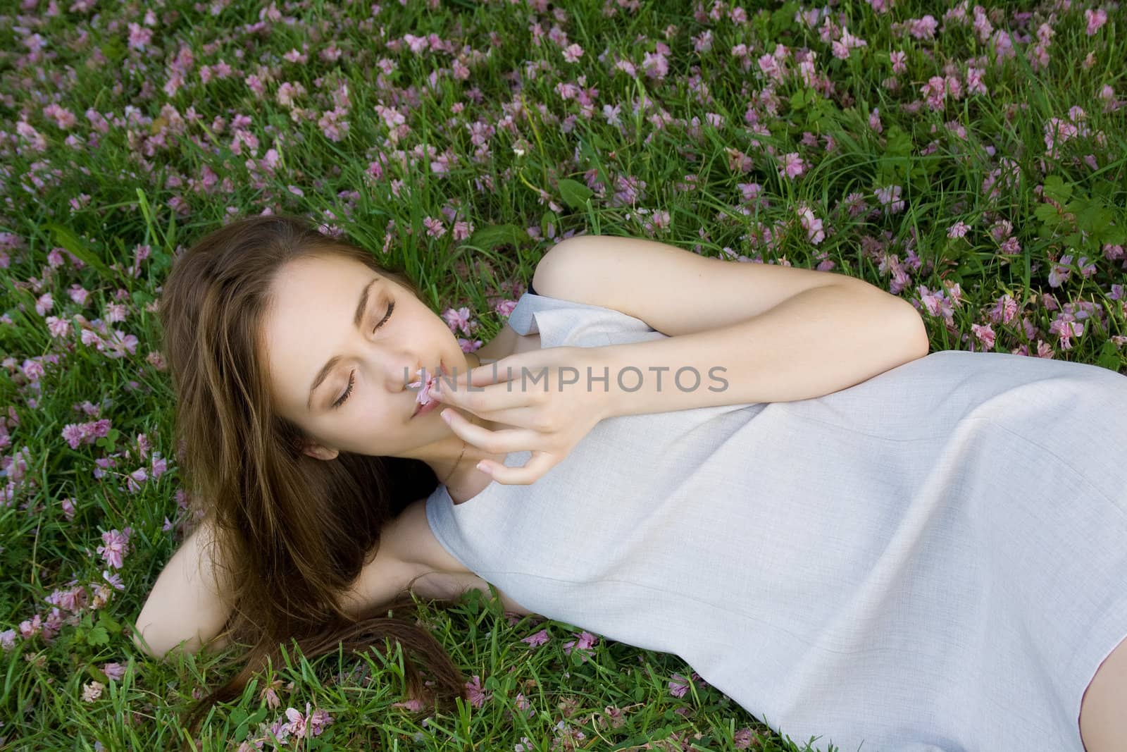 concept of harmony. Beautiful girl lying on green grass with flowers and holding a flower